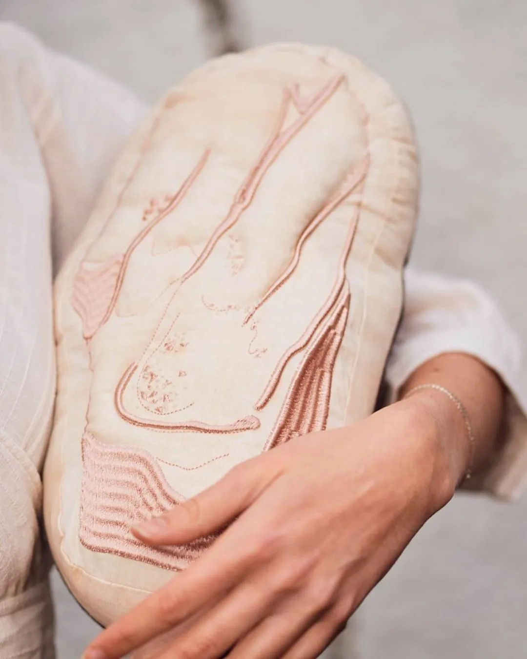 A person cradling a pillow artwork of a bean.