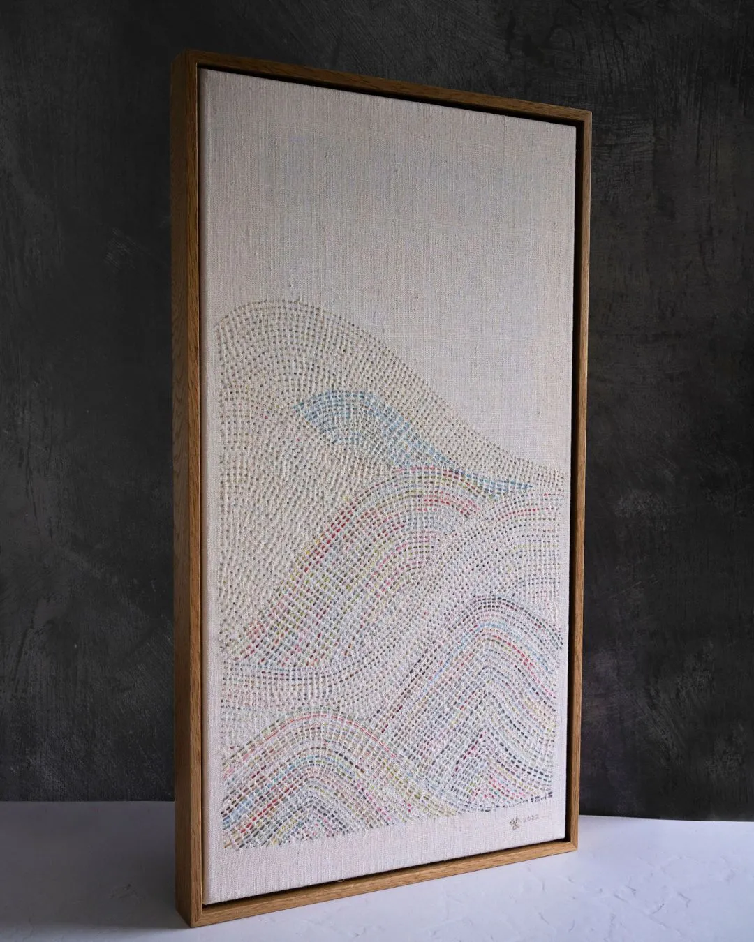 A framed artwork of a stitched wave