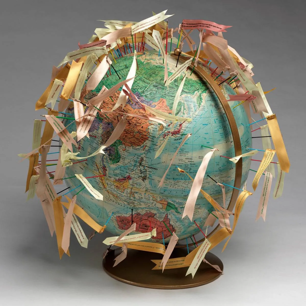 A textile art sculpture of a globe with flags pinned over its surface