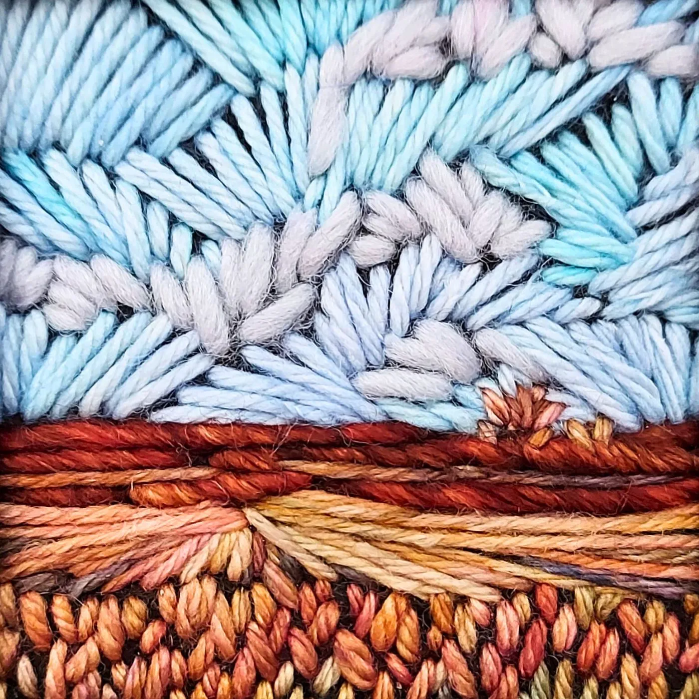 A close up of a colourful, stitched, landscape artwork.