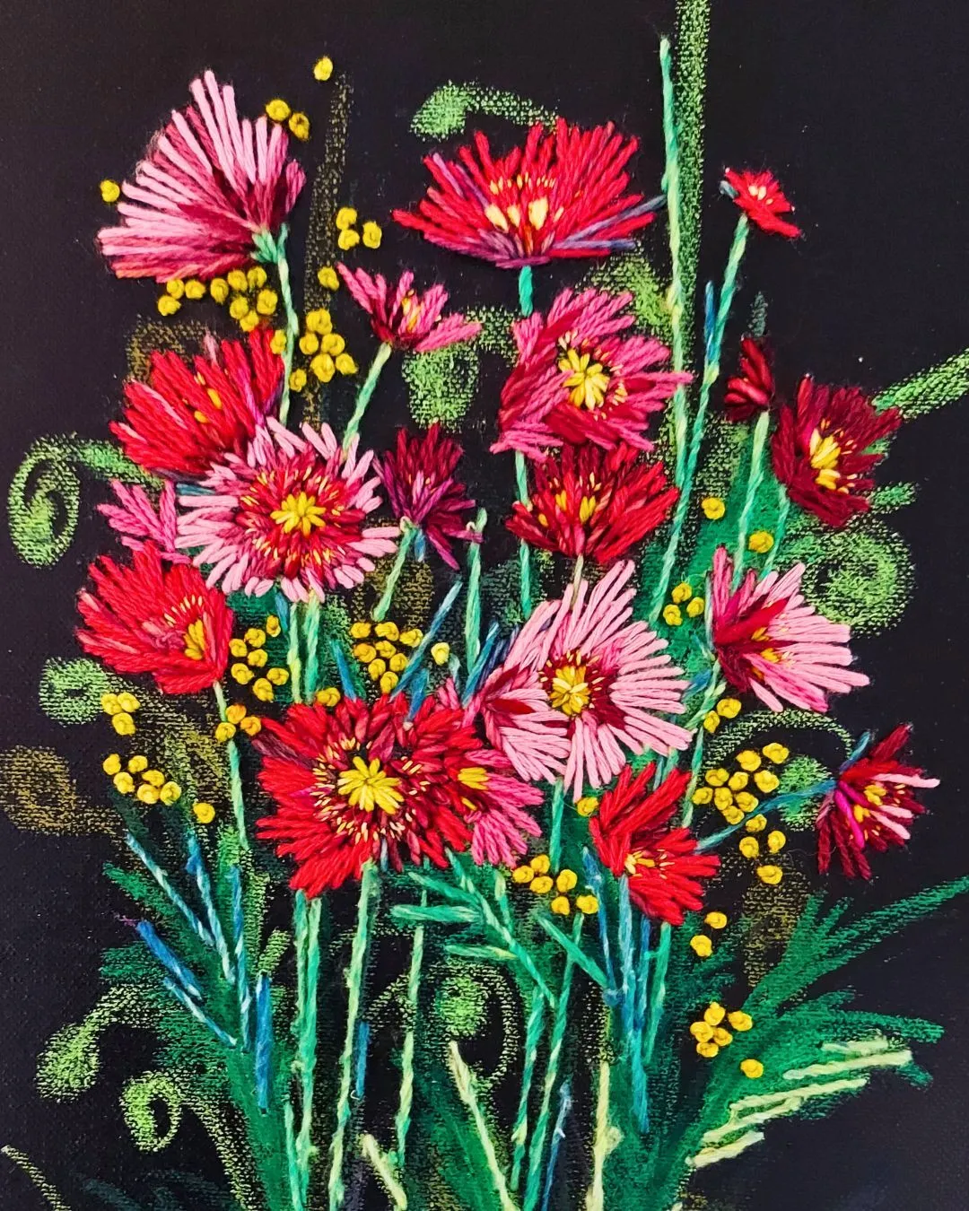 An artwork of a hsnd stitched bunch of red and pink flowers on a black background