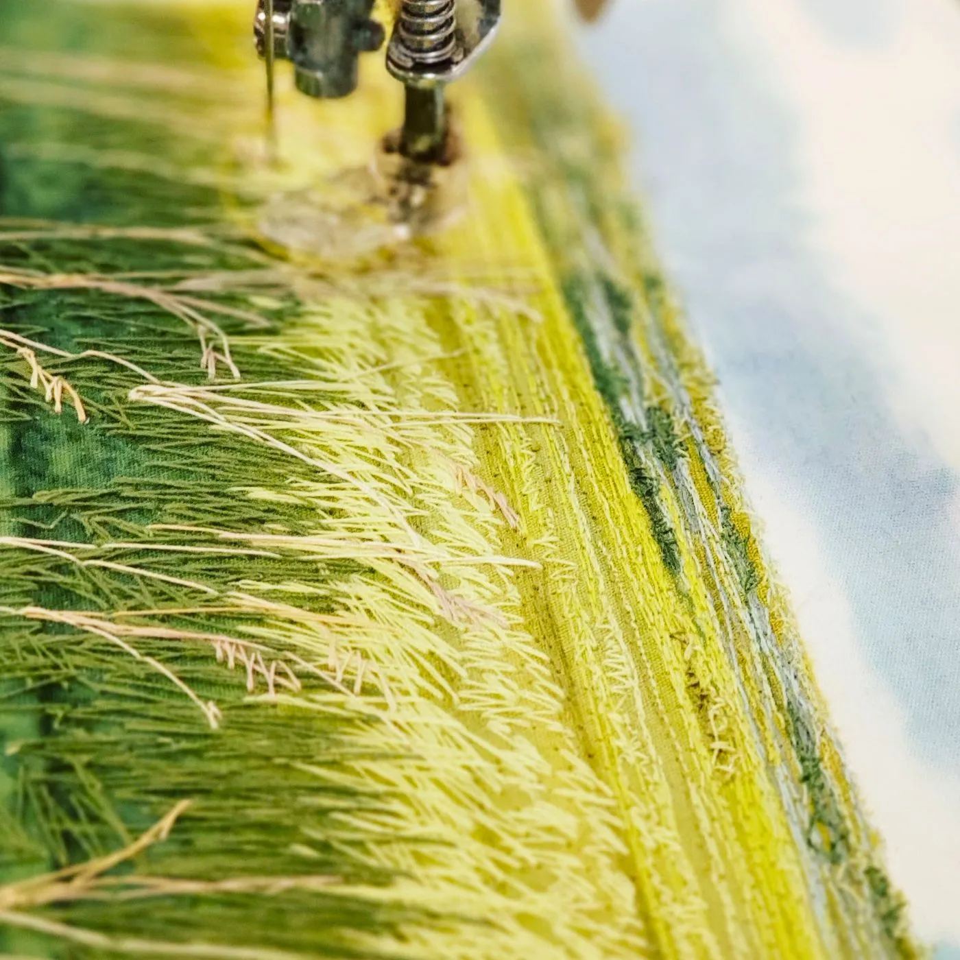 a close up of a sewing machine stitching an intricate landscape 'painting' 