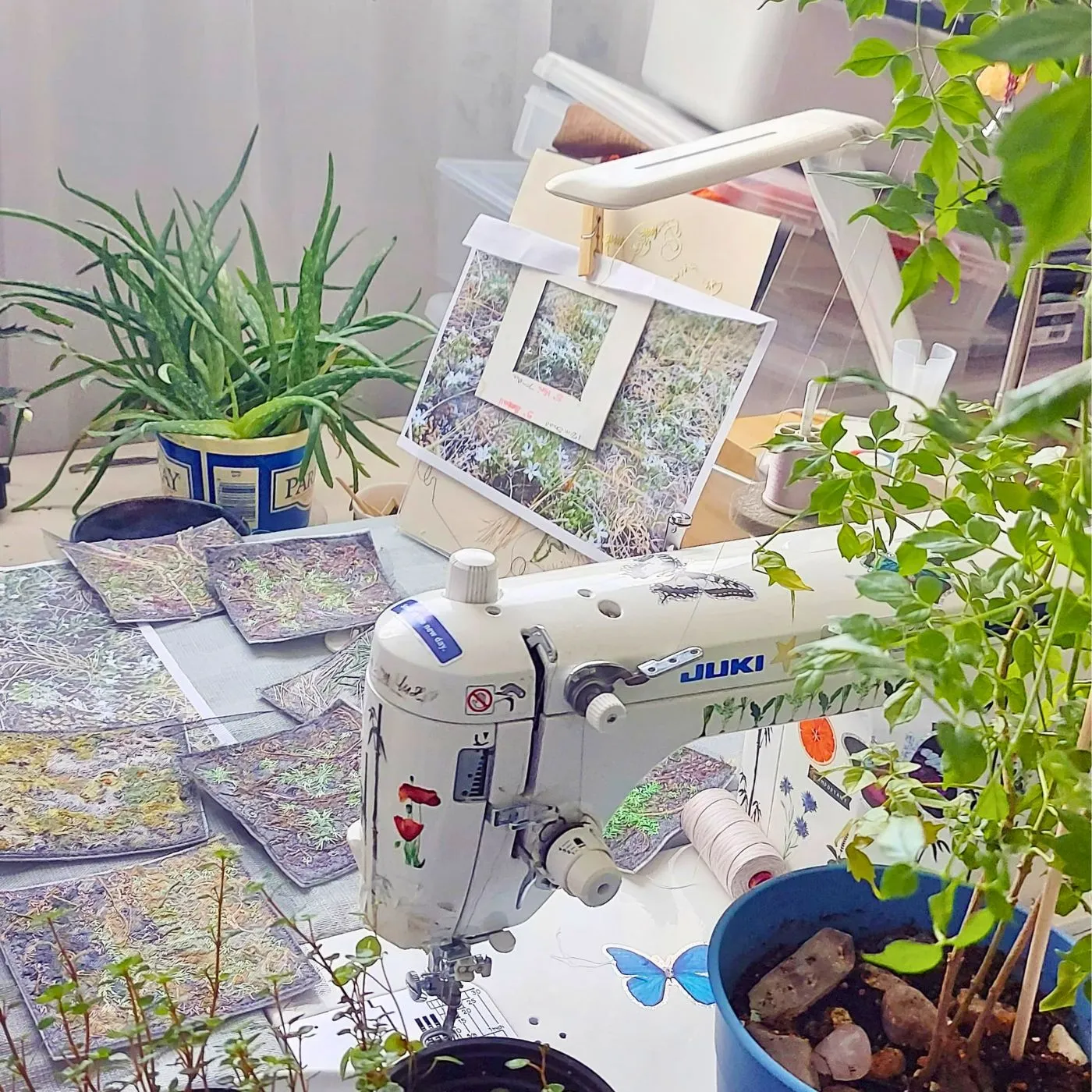 A sewing machine surrounded by plants on an artist work table