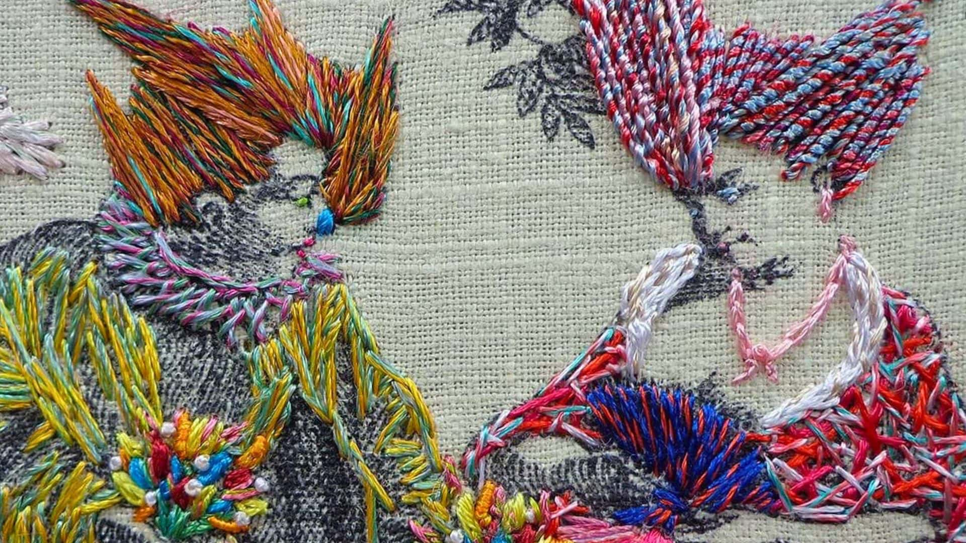 a close up of an embroidery of two people dressed in fine clothing, hand stitched with bright coloured thread.