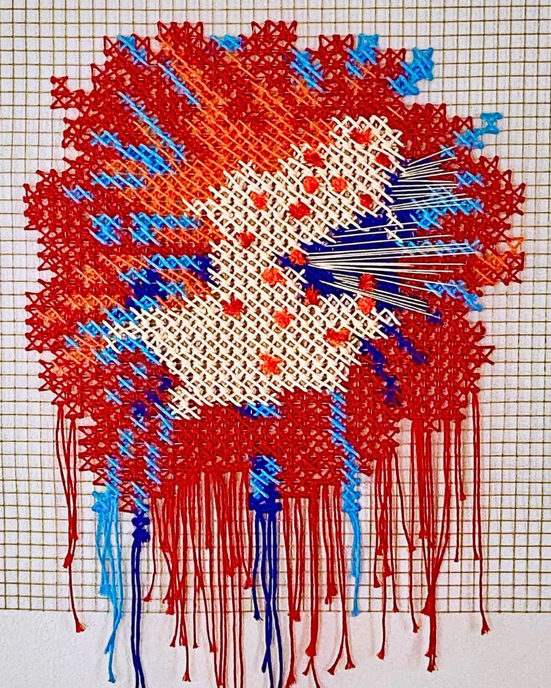 A red white and blue art piece, hand embroidered on wire mesh.