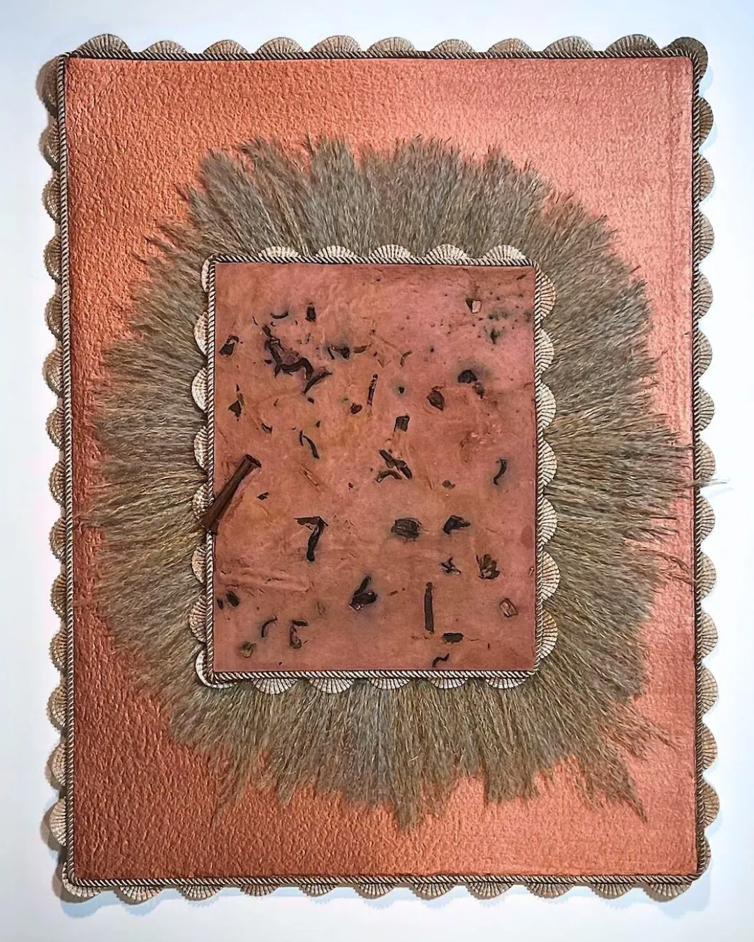 A brown and peach coloured rectangular textile art piece framed with a fringed edge