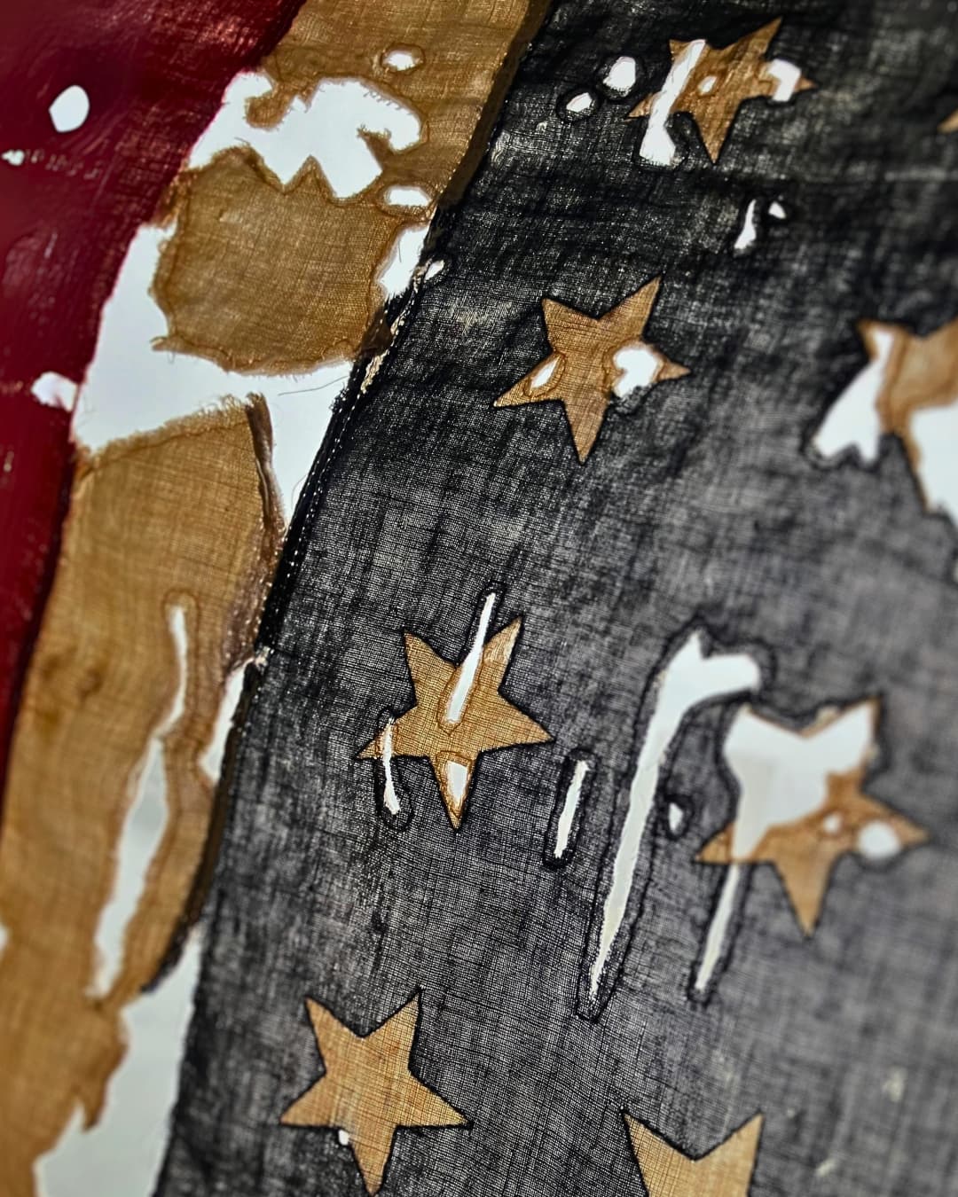 A close up image of an American flag, frayed and degraded with lots of holes