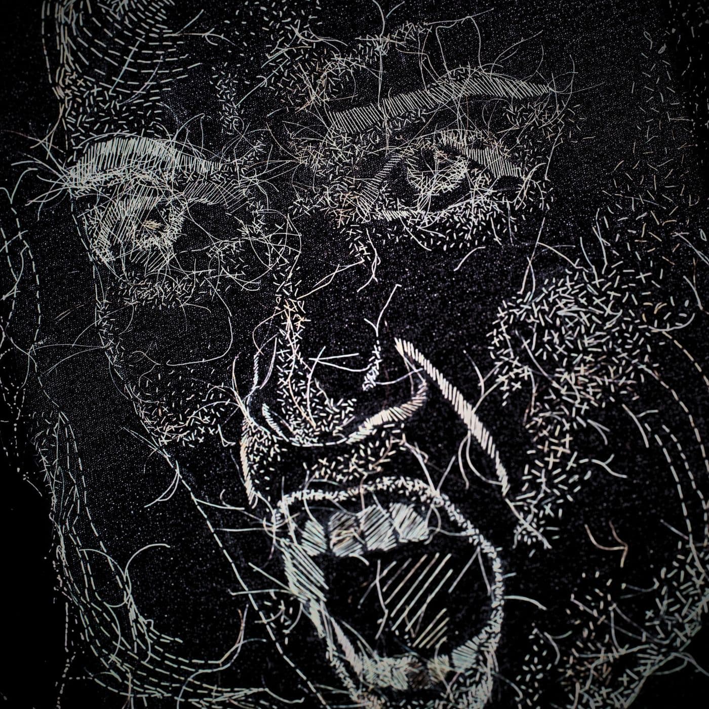 A close up of a stitched artwork of a face, screaming.