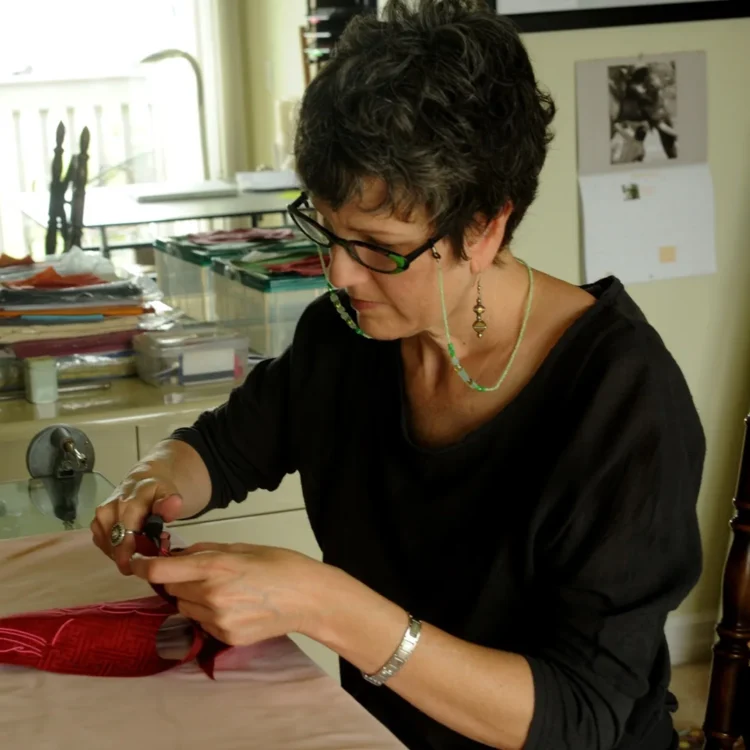 Leslie Rinchen-Wongmo cutting pieces of a silk thangka in her home studio, 2012.