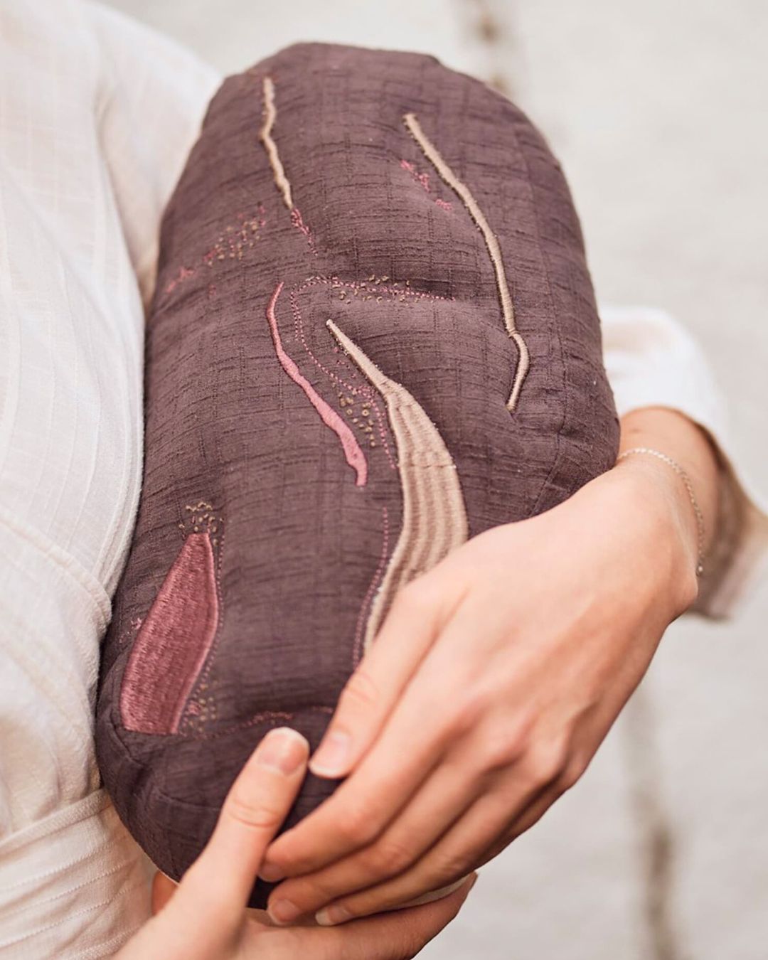 A person cradling a pillow artwork of a bean.