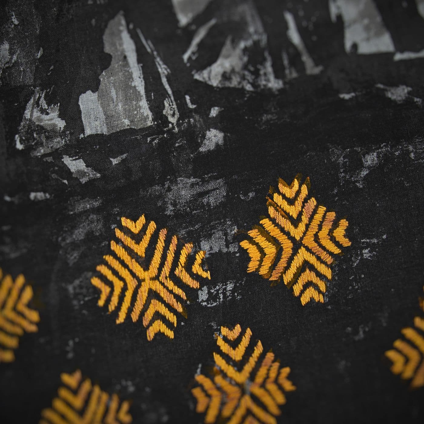 A close up of a black fabric with gold diamond stitched embellishments.