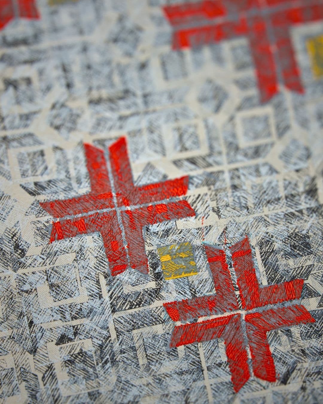 A close up of a red and grey stitched artwork