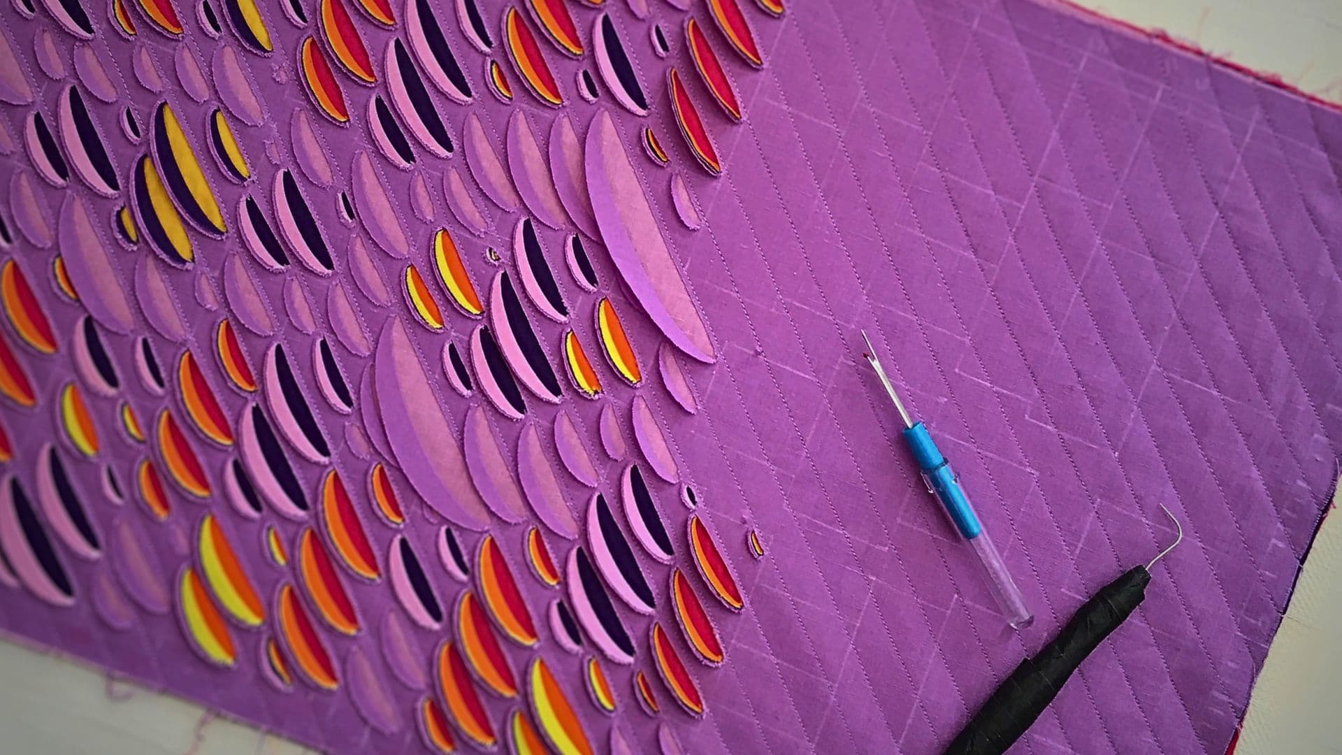 A purple fabric with a patchwork pattern 'in progress'.