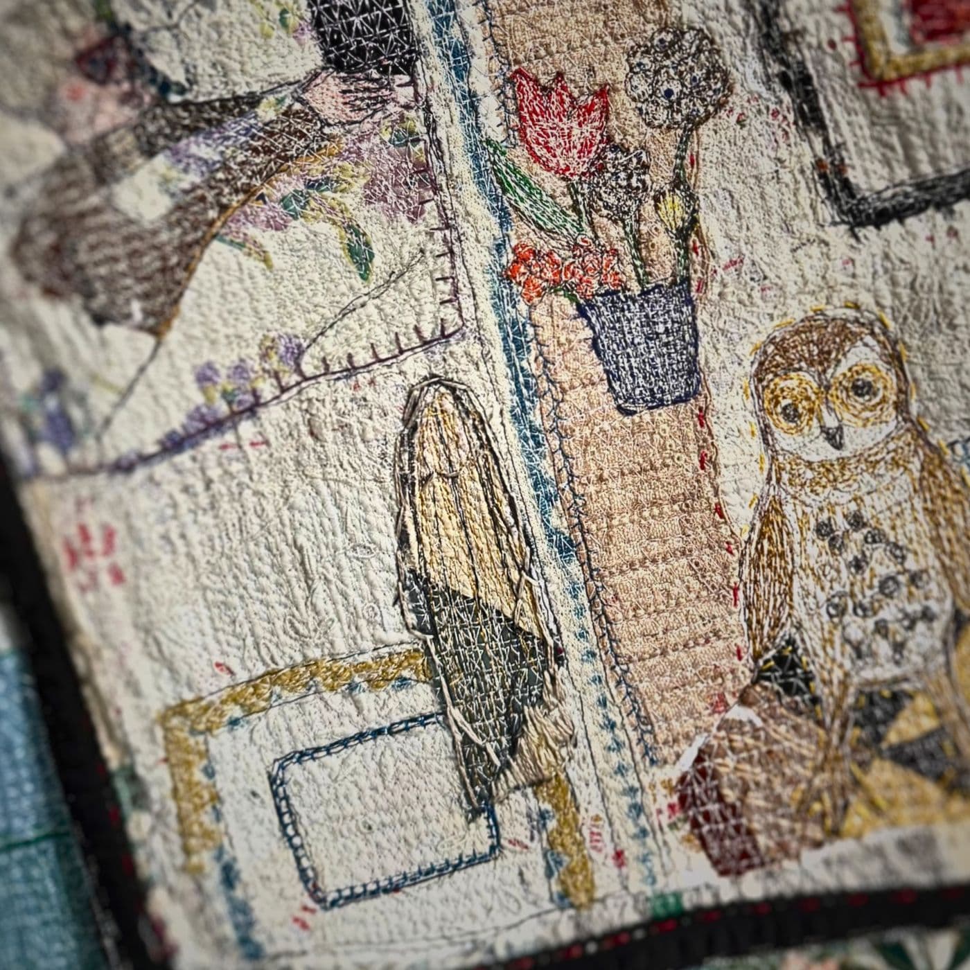 A close up of a stitched owl and flowers.