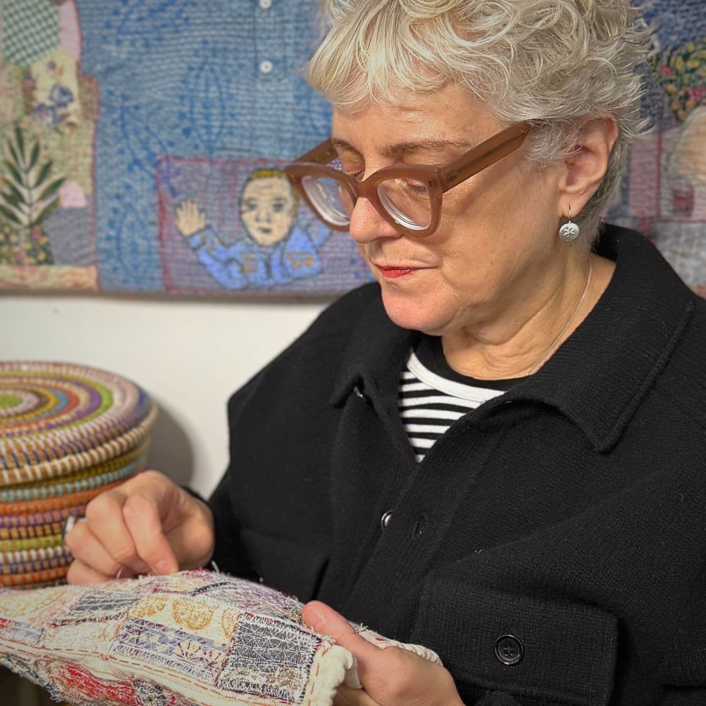 A close up of Anne Kelly sewing a piece of fabric in her studio.