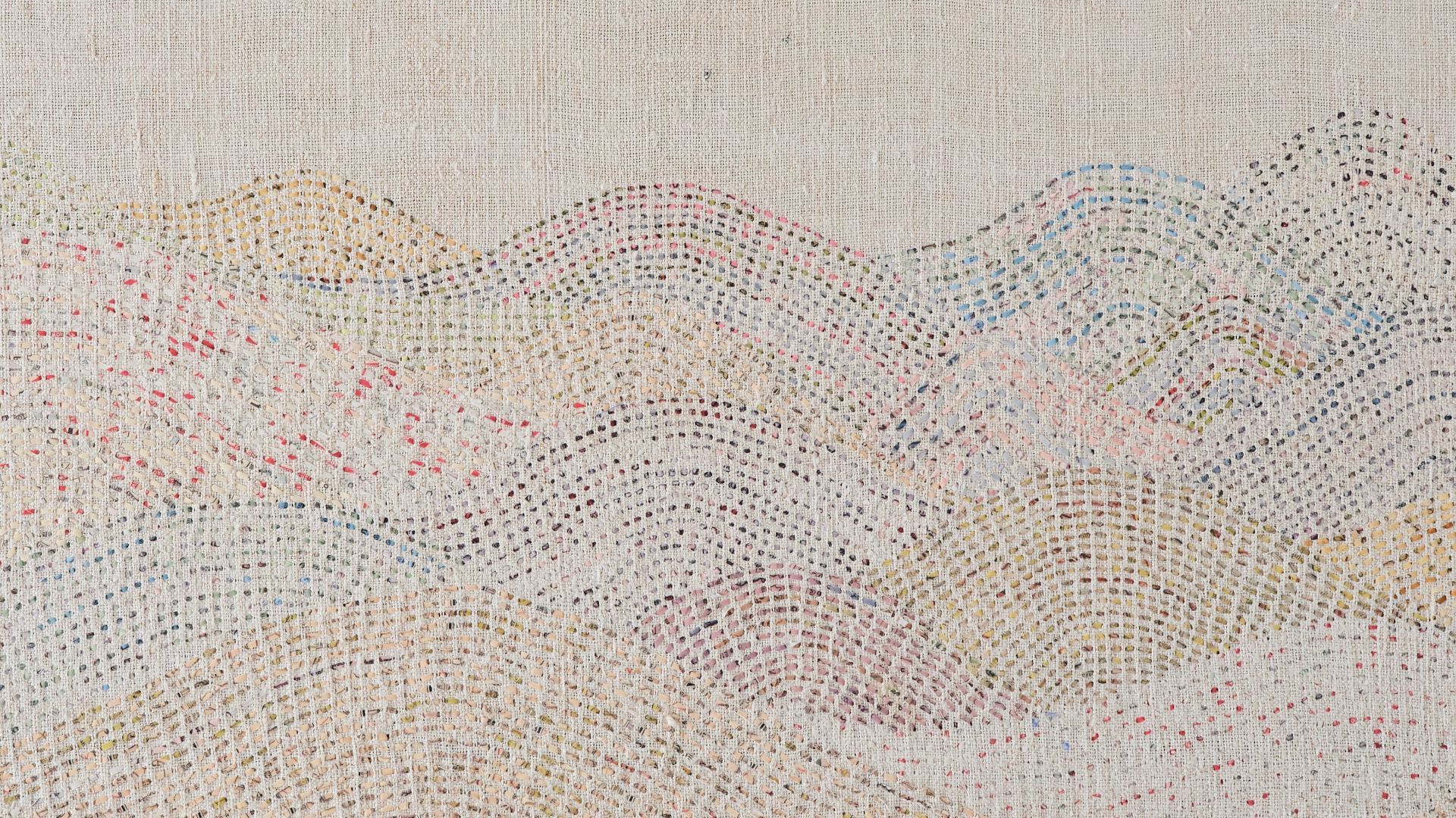 A close up detail of a stitched artwork representing a delicate mountain range on linen