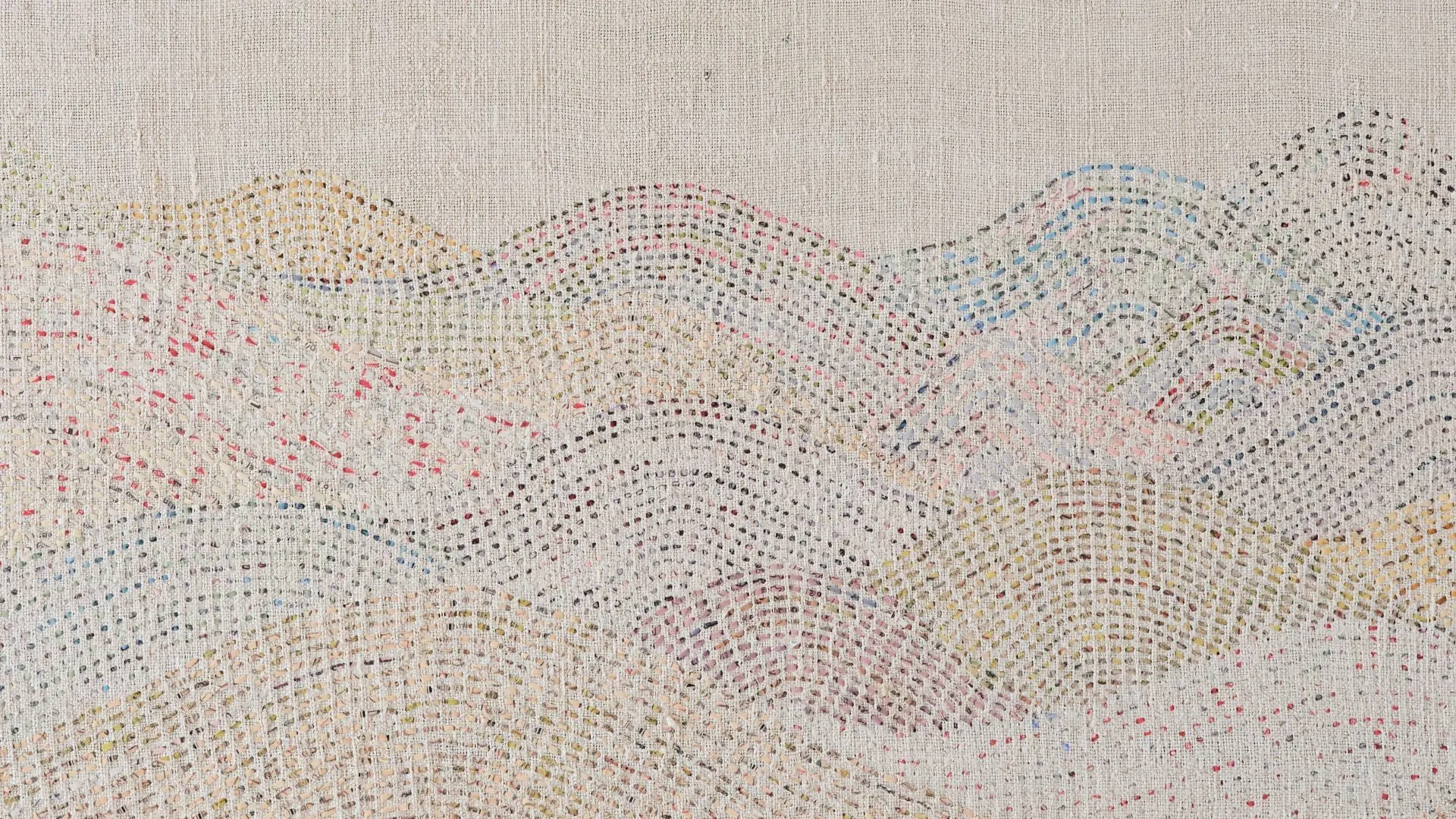 A close up detail of a stitched artwork representing a delicate mountain range on linen