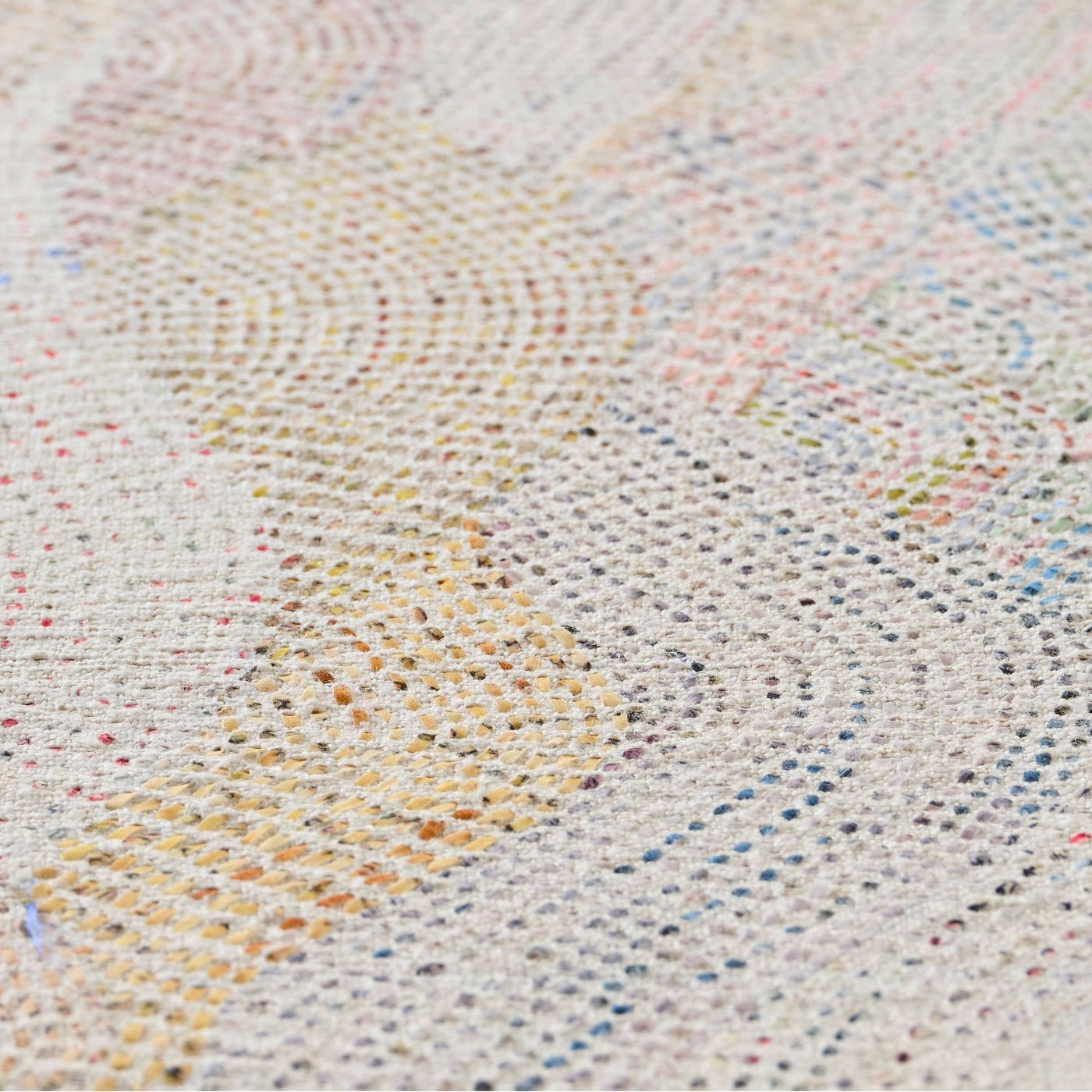 A close up detail of a stitched artwork representing a delicate mountain range on linen