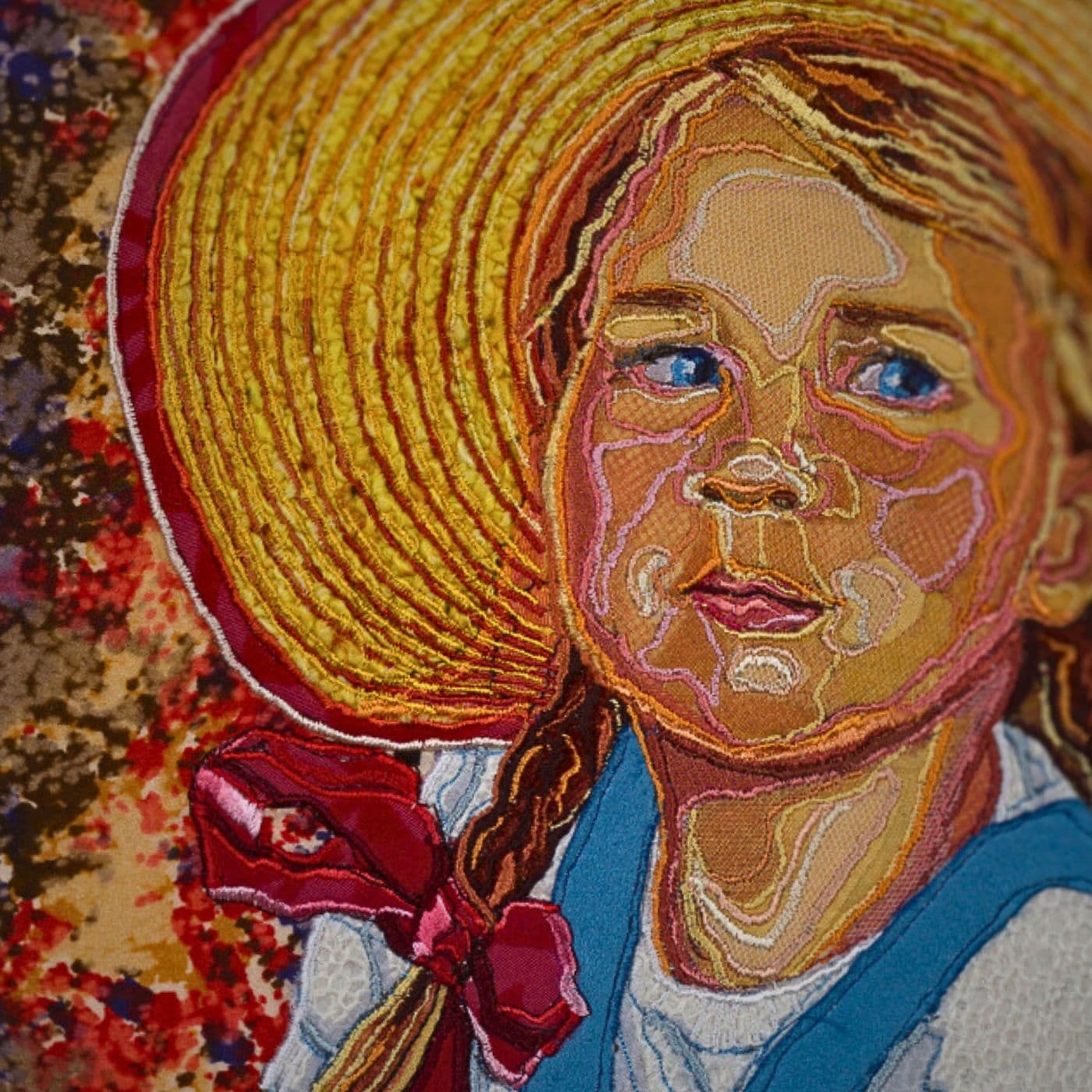 A close up of a stitched artwork of a young girl in a straw hat, looking off to the side.