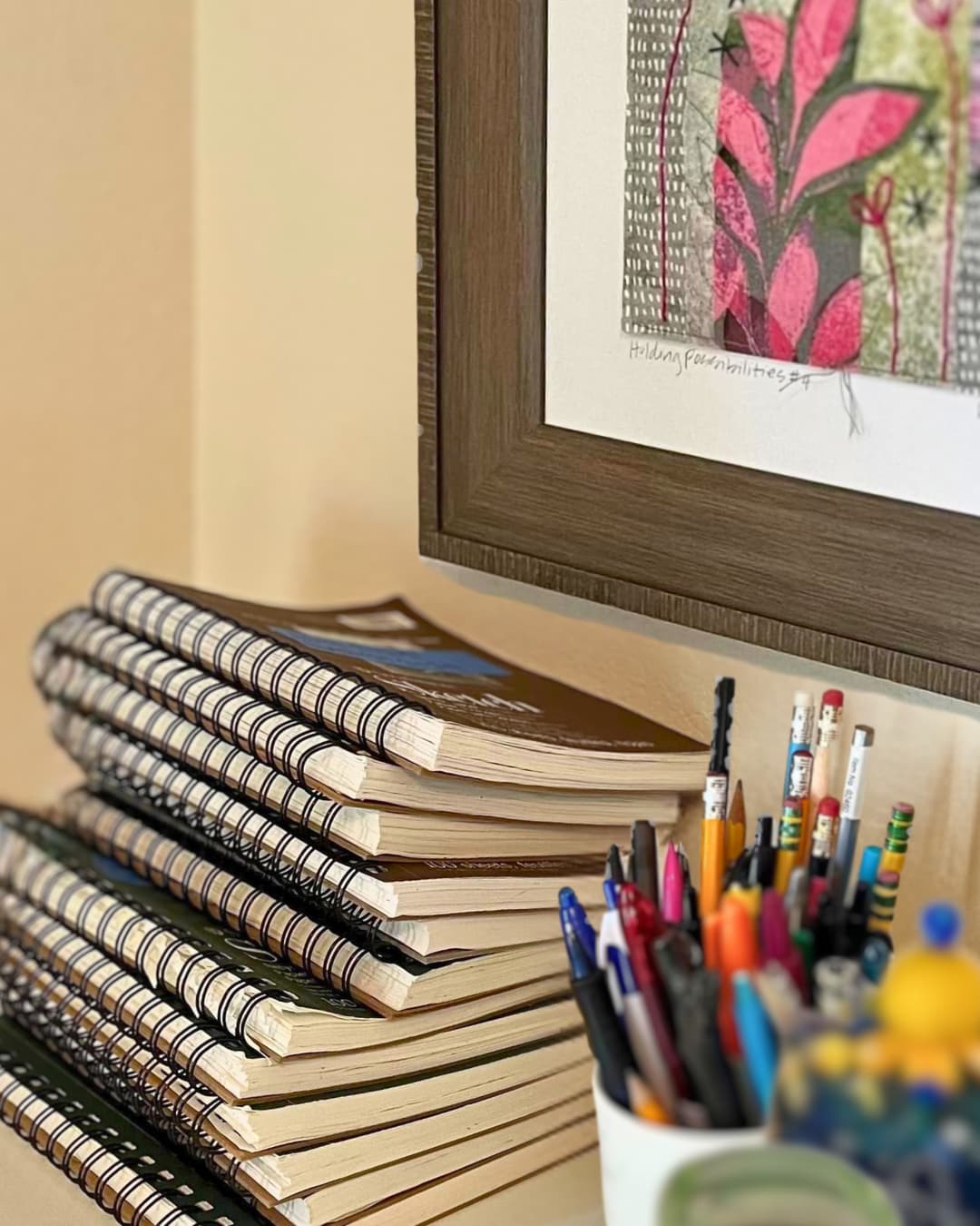 A stack of notebooks and pens in a holder