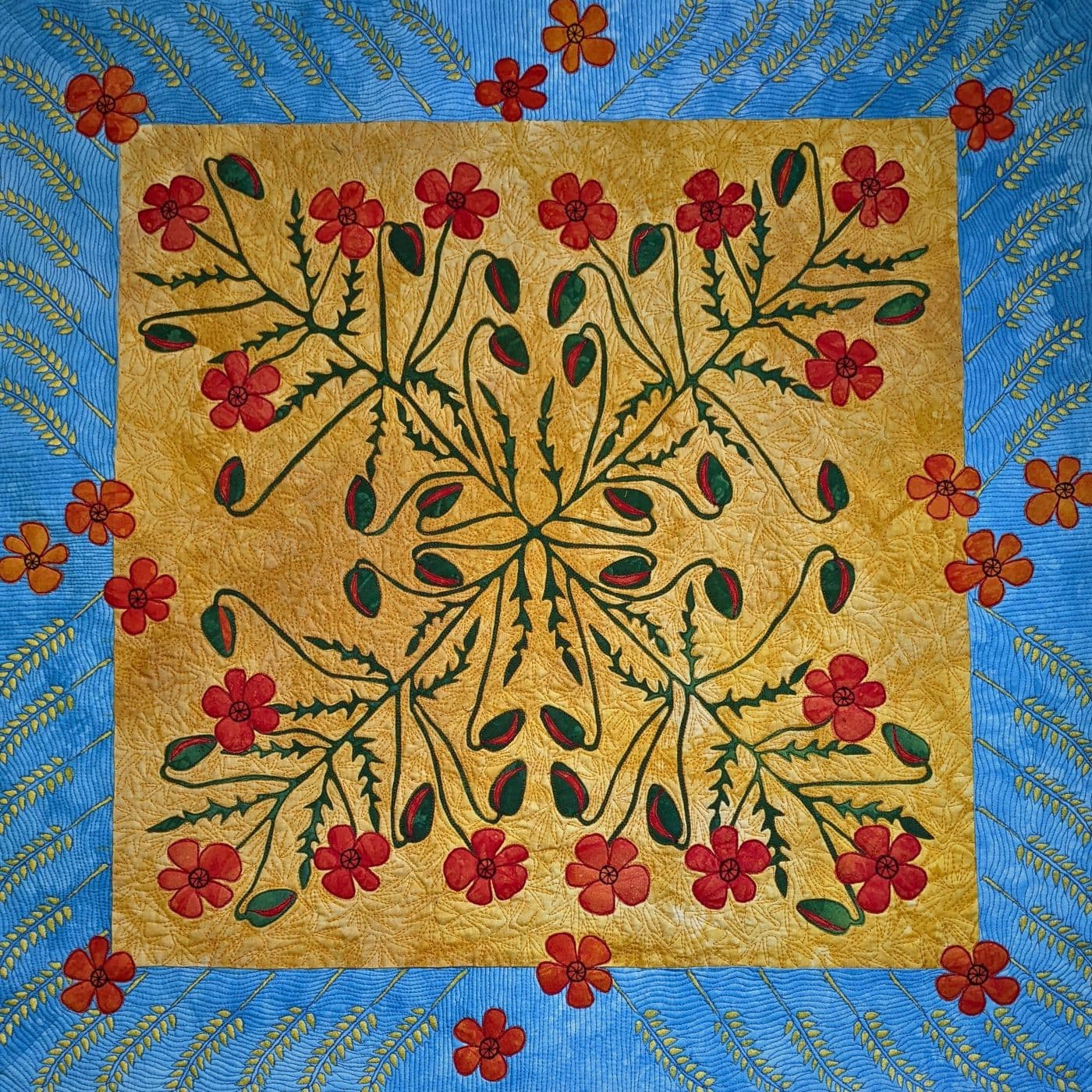 A stitched art quilt of a cross within a square pattern embellished with flowers.