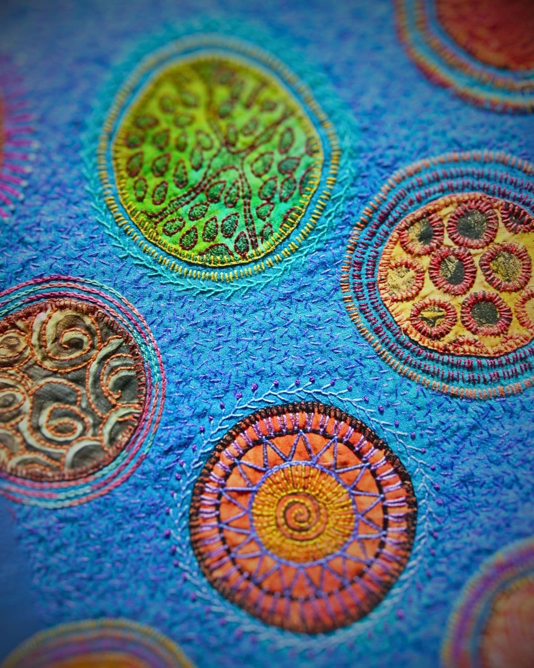 A close up of a blue fabric embroidered with colourful circles.