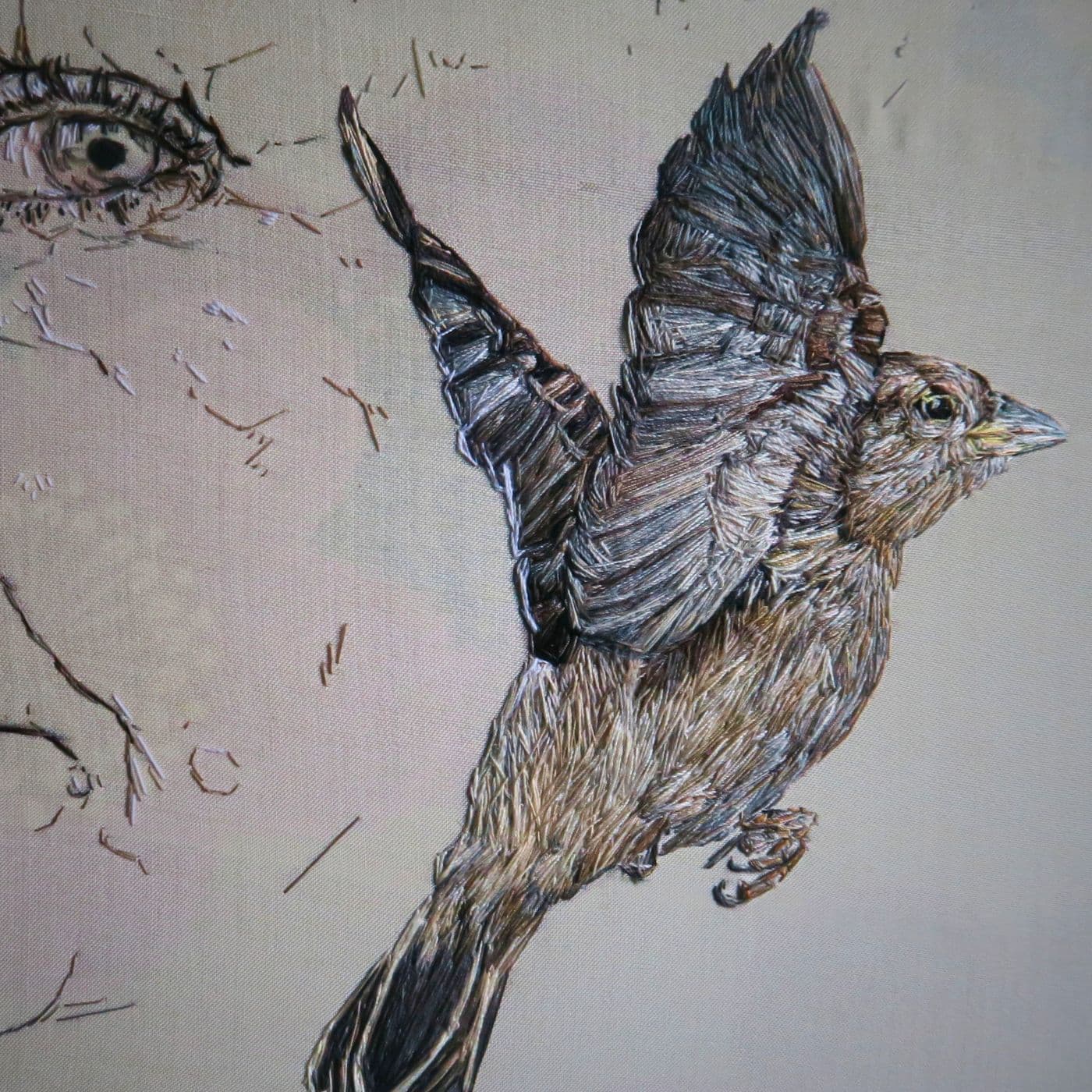 A bird with wings spread and eyes drawn on fabric