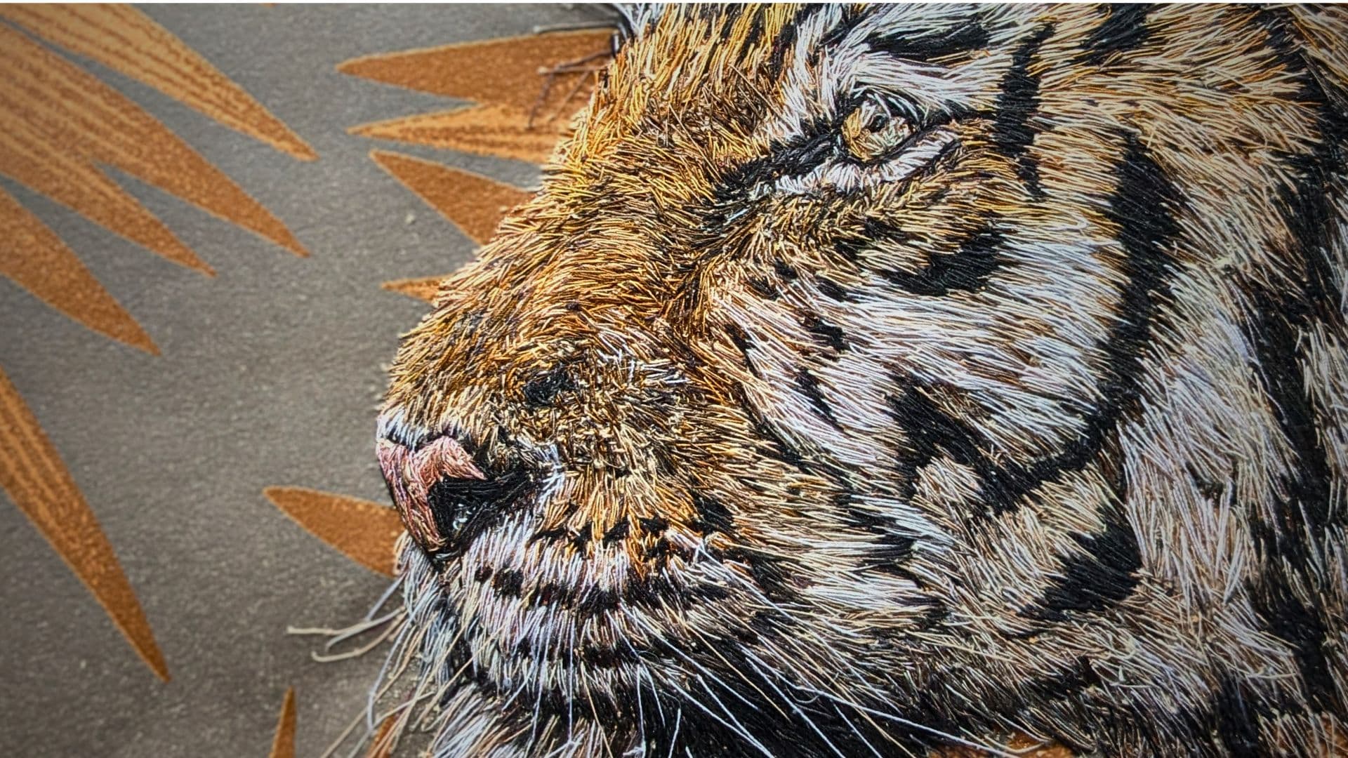 A close up of a stitched artwork of a tiger's face