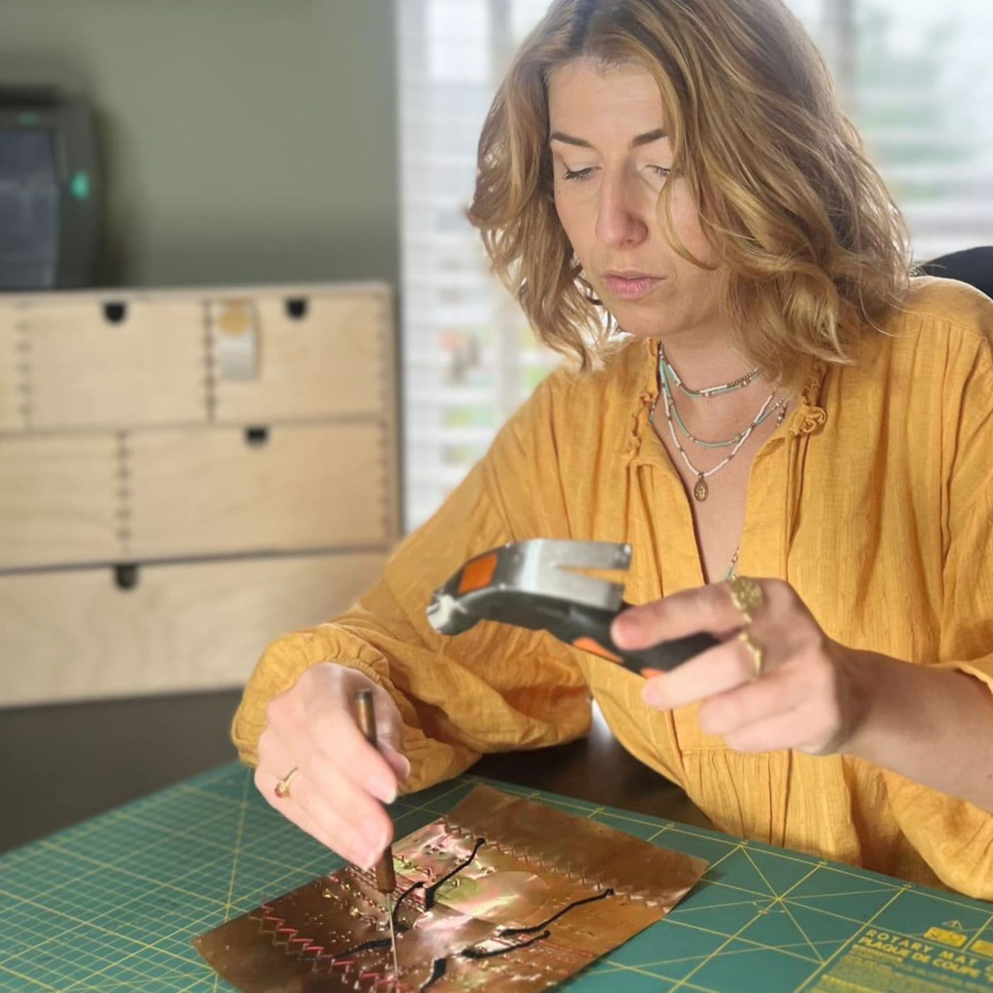 Emma Pannell hammering holes into rolled aluminium in her studio.