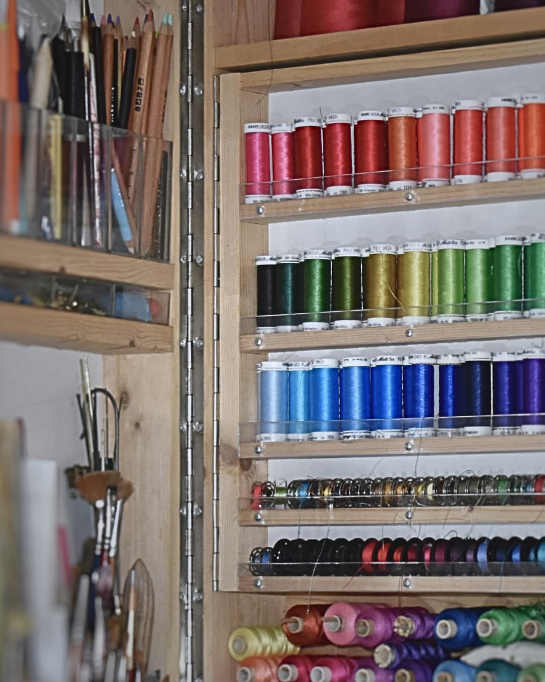 A storage unit with colourful spools of thread and artist's materials