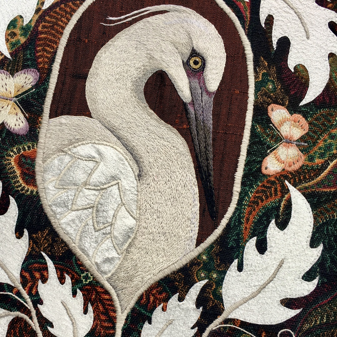 An embroidery of a white bird with a butterfly on it.