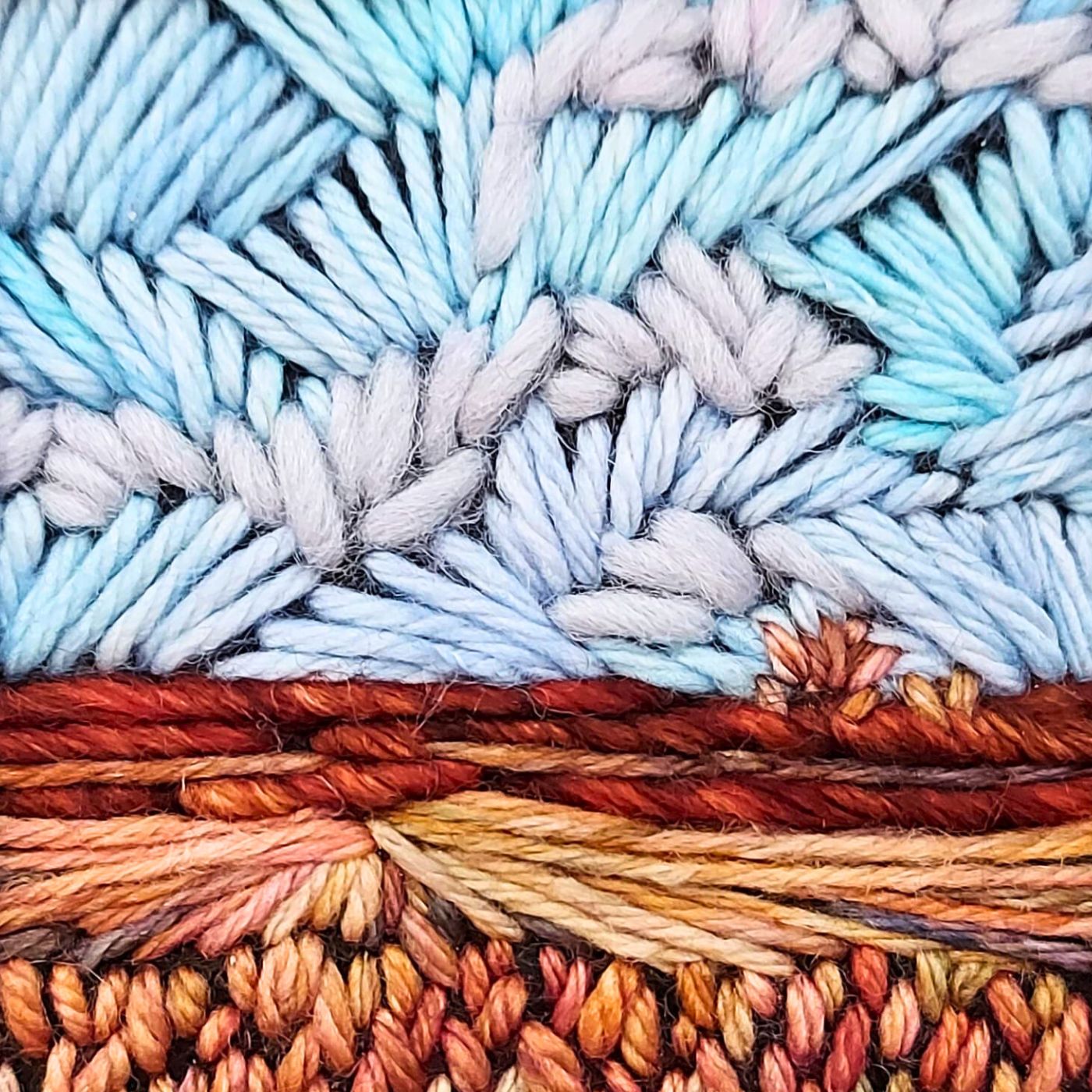 A close up of a colourful, stitched, landscape artwork.