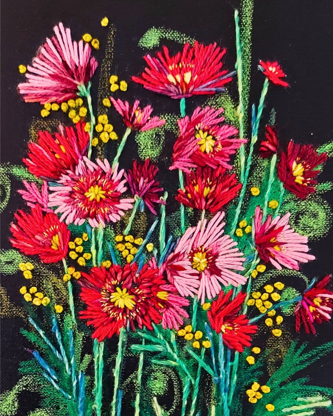 An artwork of a hsnd stitched bunch of red and pink flowers on a black background