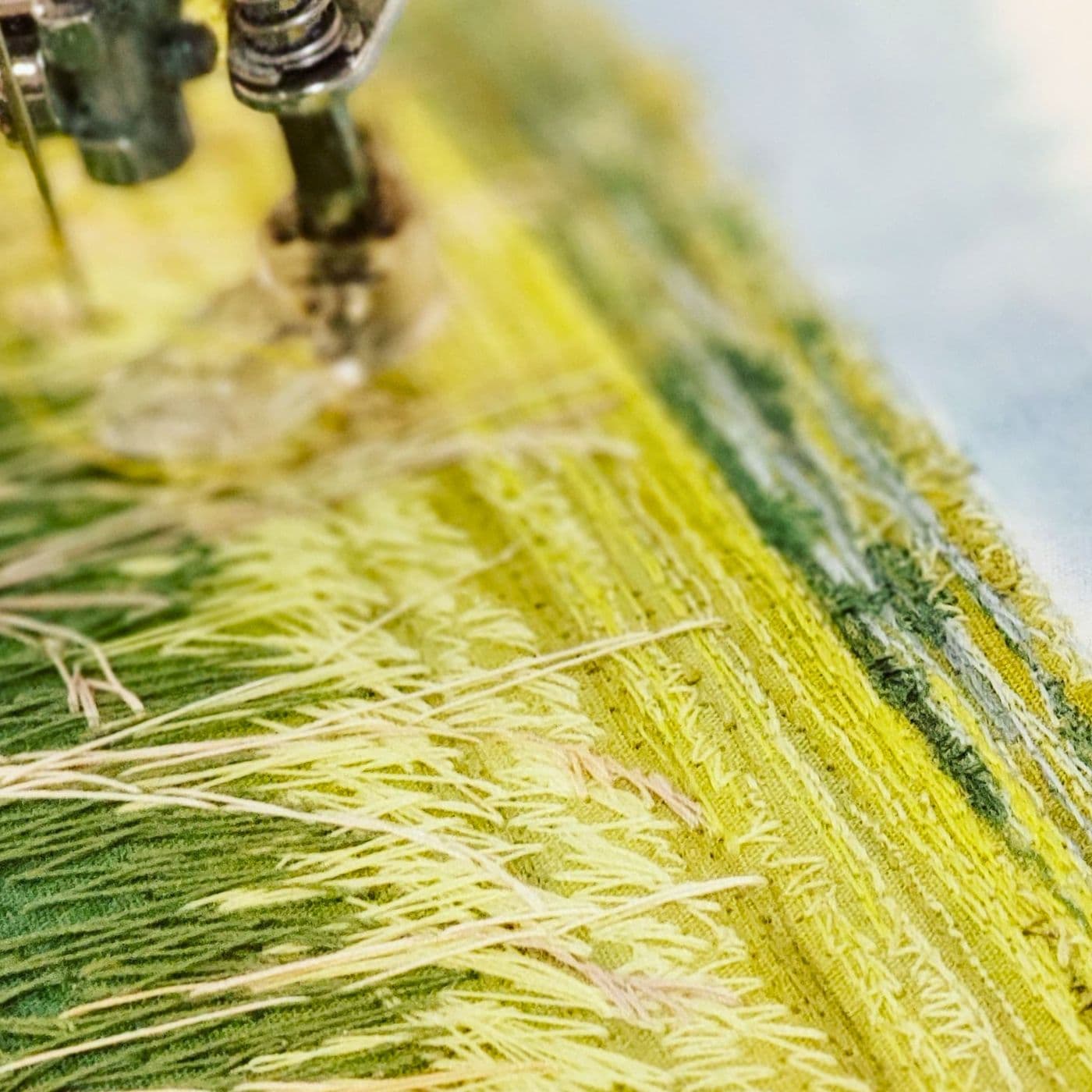 a close up of a sewing machine stitching an intricate landscape 'painting' 