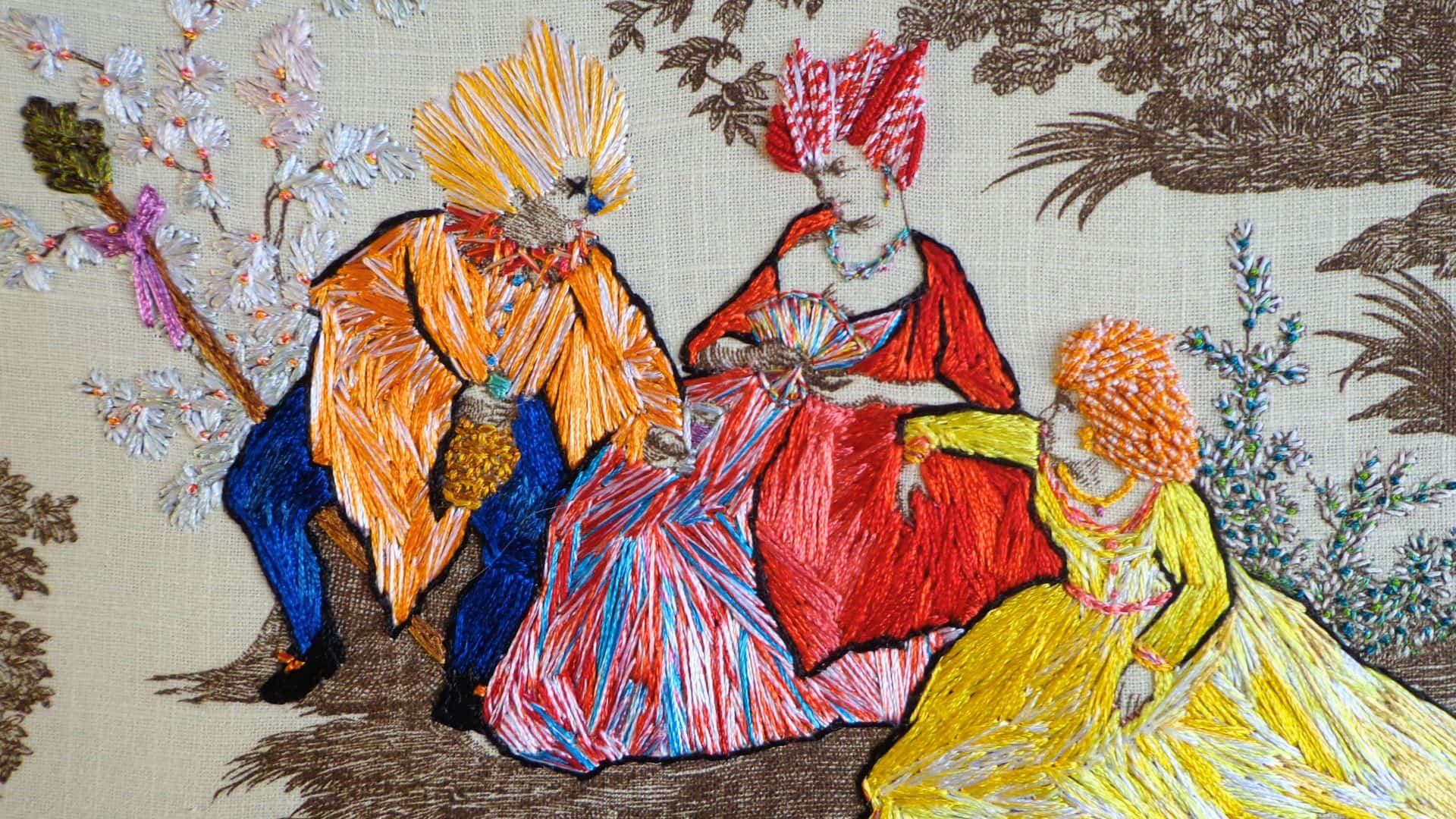 a hand-stitched image of a group of people in colourful dresses sat down in conversation.