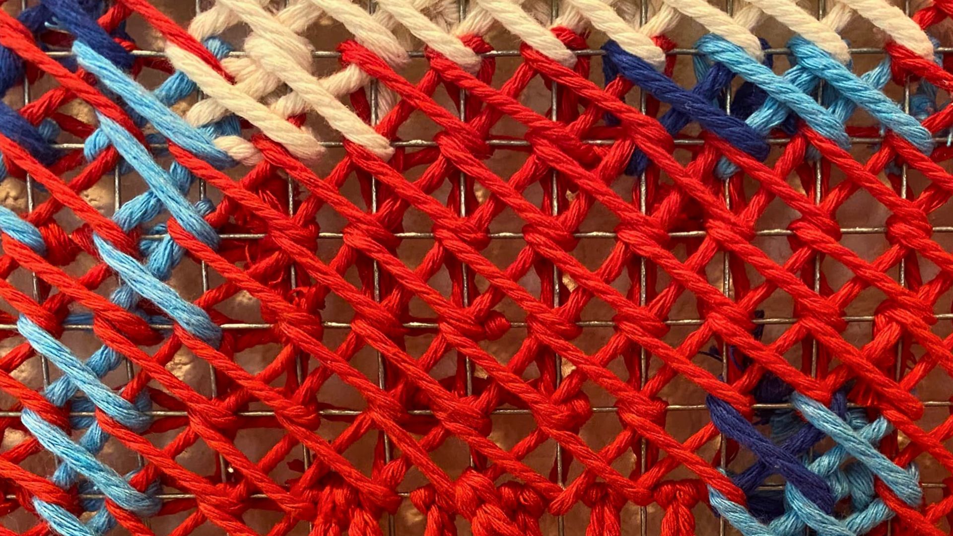 A close up image of red, blue light blue and cream coloured woven fabric.