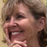 A close-up image of textile artist Robin McCarthy smiling with her hand on her chin