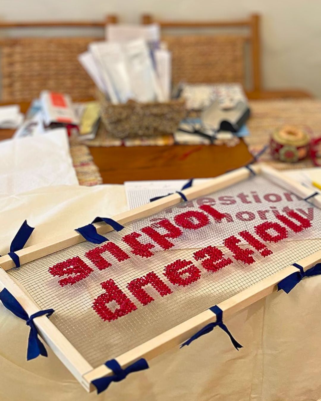 Robin McCarthy’s kitchen table, which also acts as her desk and sewing table. A close up of a stitched artwork on a table.