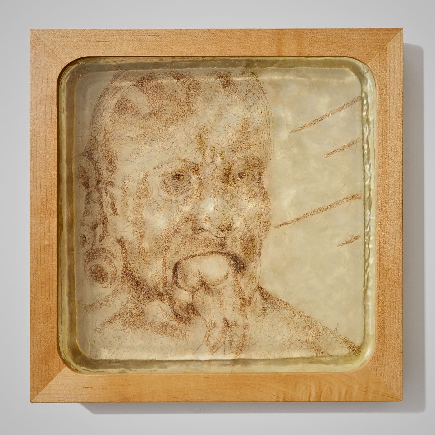 An artwork of a person's face with a smaller person in their mouth. Stitched in human hair.