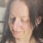 Close-up portrait of Ruth Norbury, a textile artist, deeply engaged in her detailed embroidery work