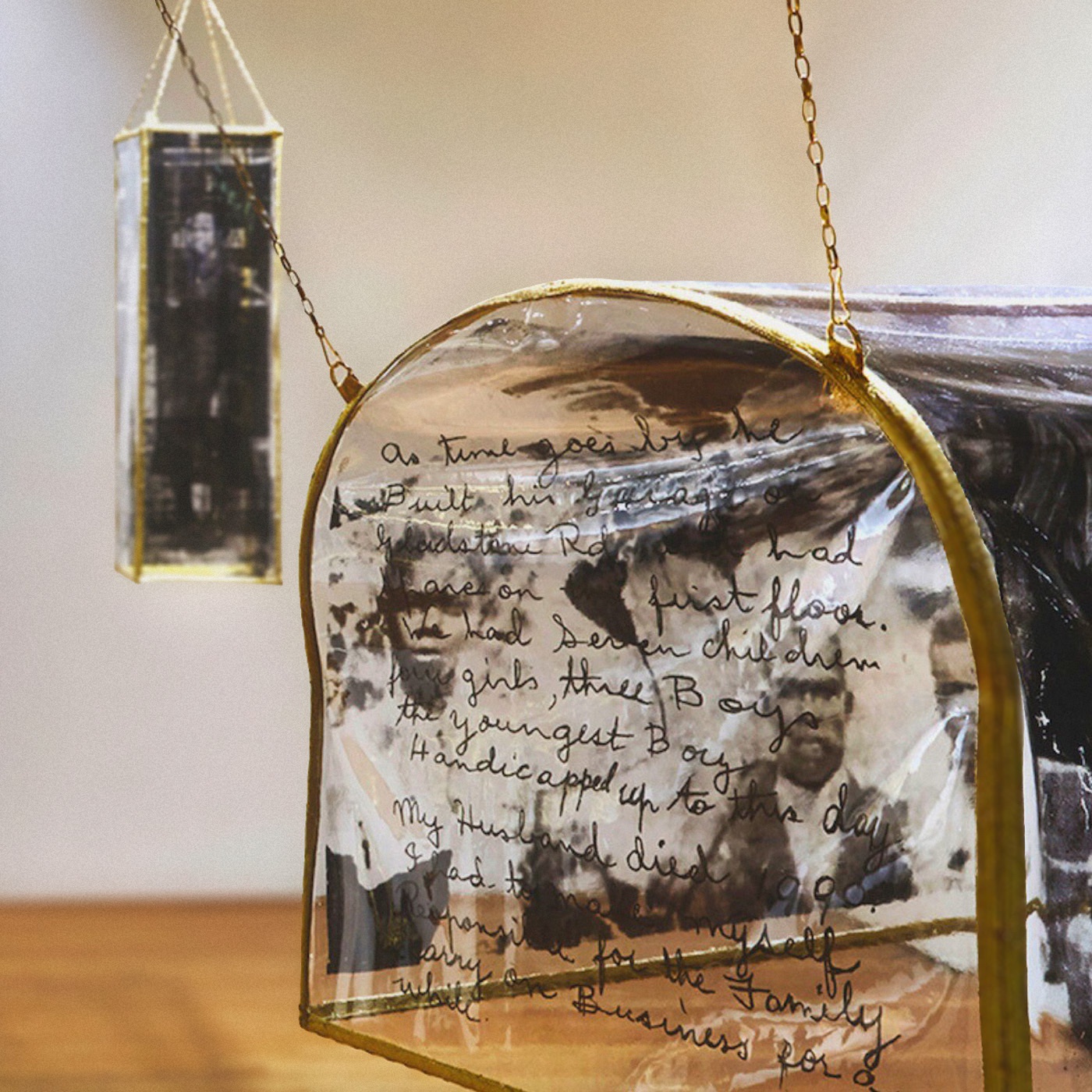 An installation artwork with printed pictures of people and handwriting on PVC hanging in a gallery