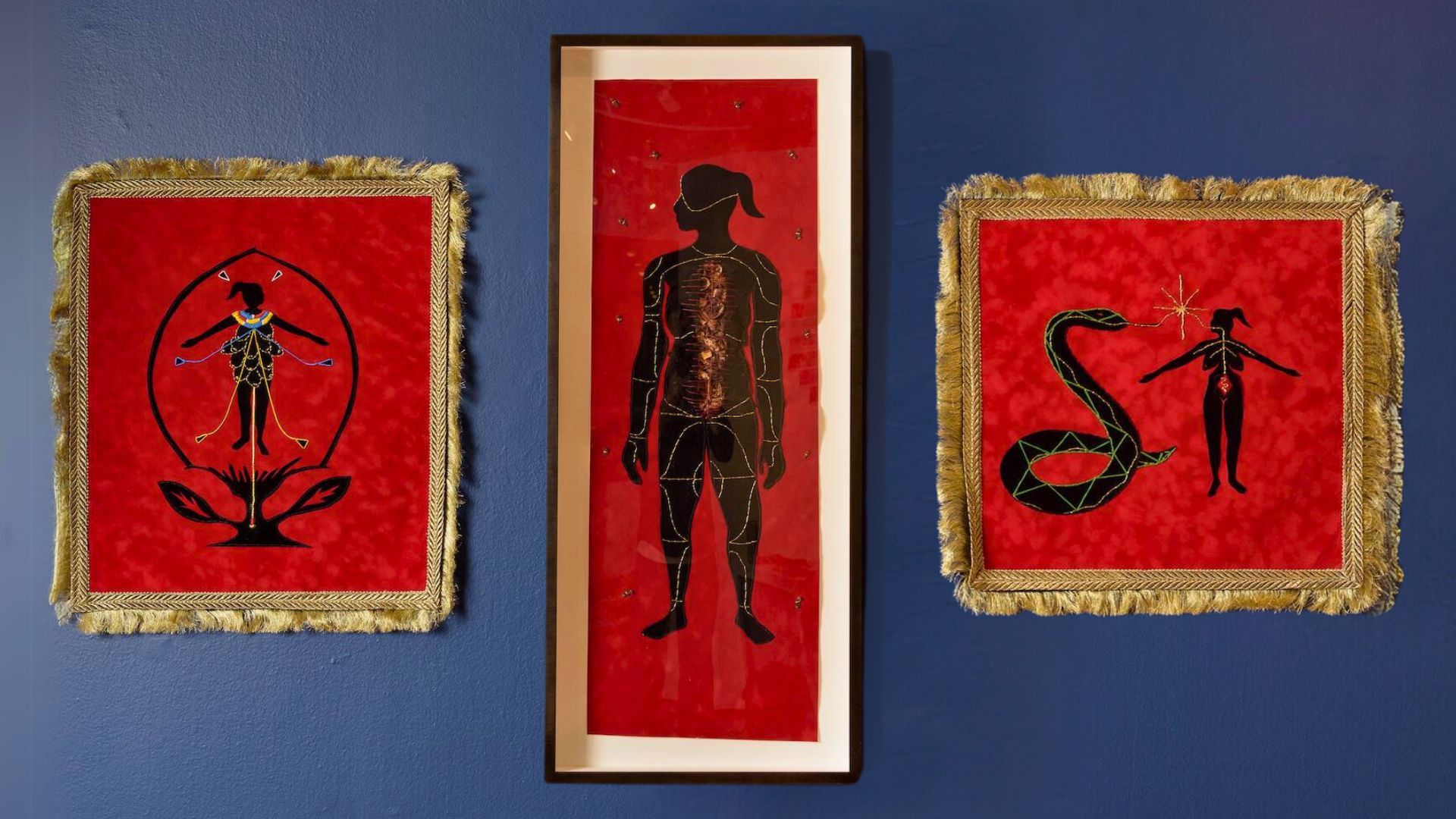 Three framed artworks depicting the silhouettes of a person and a snake on red backgrounds