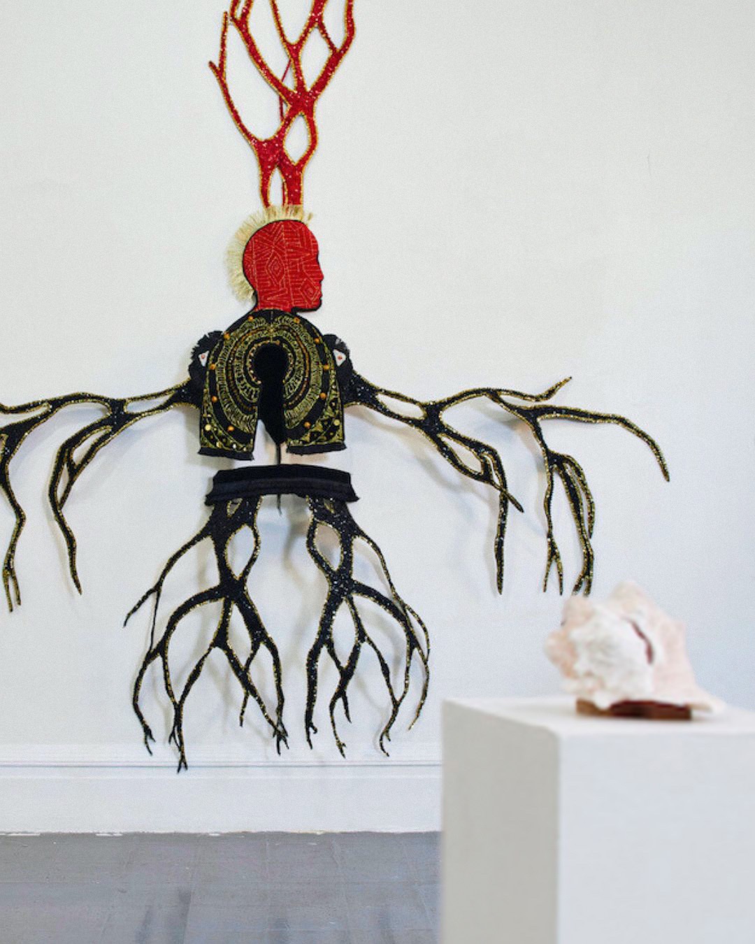 A modern textile art sculpture hanging on a gallery wall