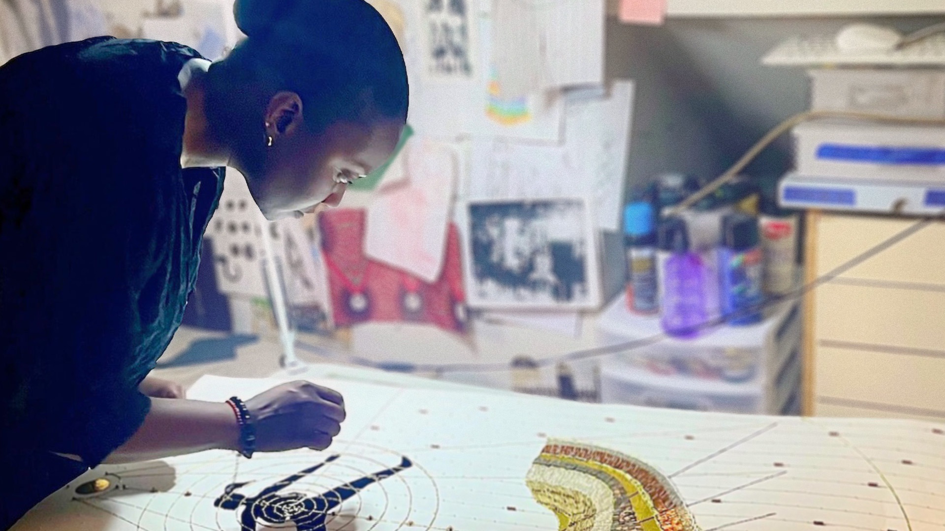 A female textile artist stitches a large artwork on her studio table