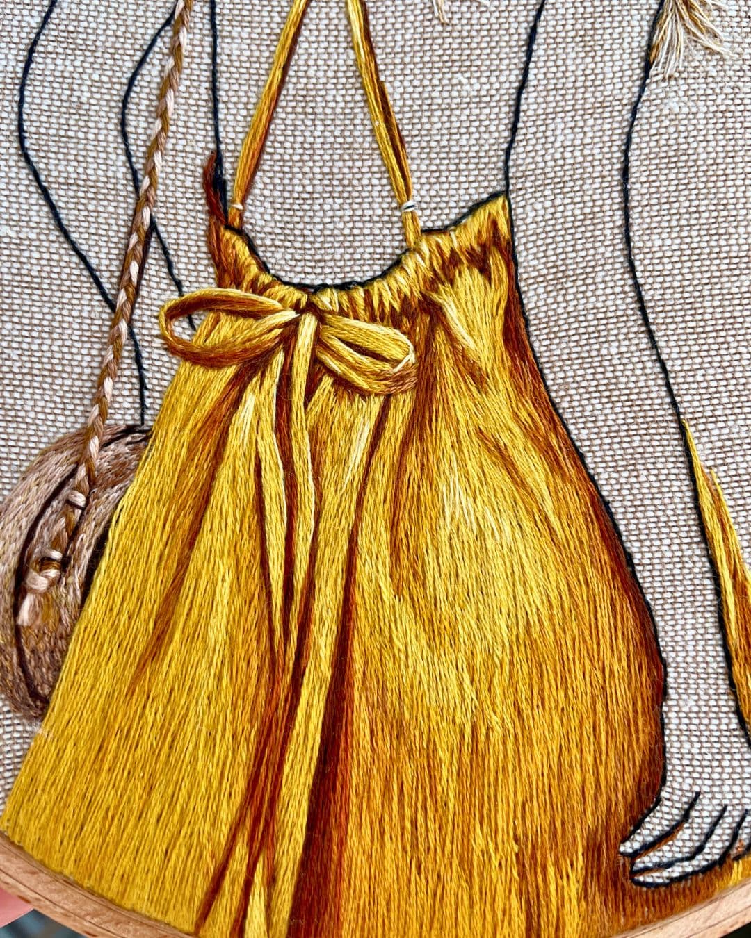 A close-up image of a stitched artwork of a woman wearing a bright yellow outfit.