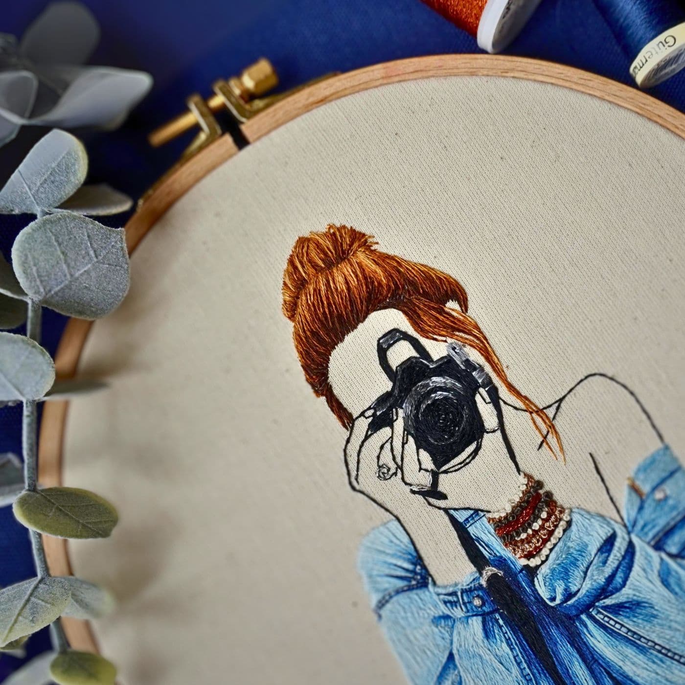 An embroidery of a woman with a camera in her hand.