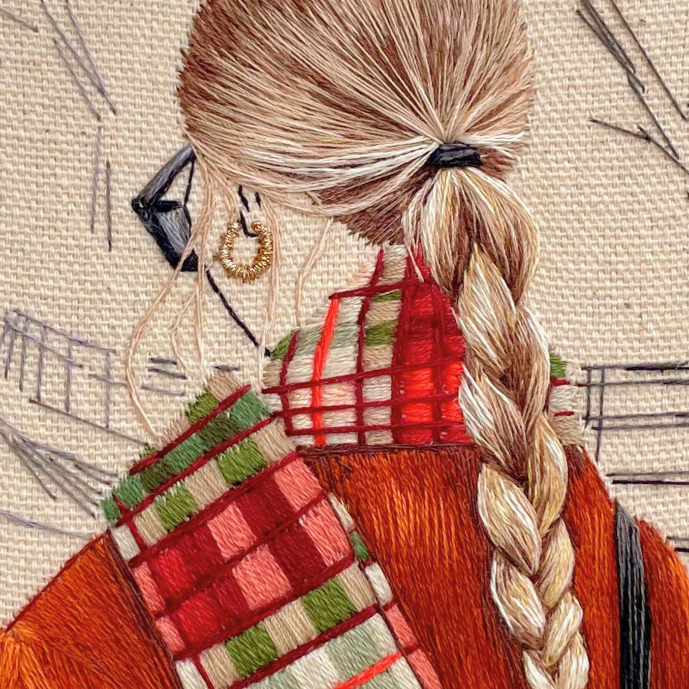 A close up stitched artwork of a girl with a tartan scarf. 