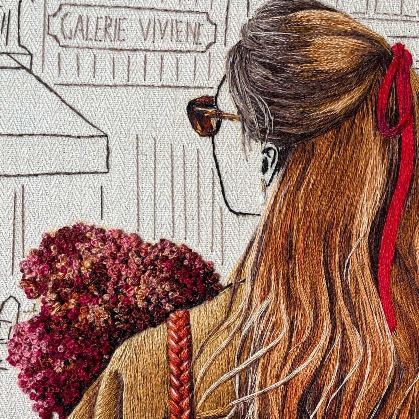 A close-up of a stitched artwork of a woman with a bouquet of flowers standing in front of a restaurant.