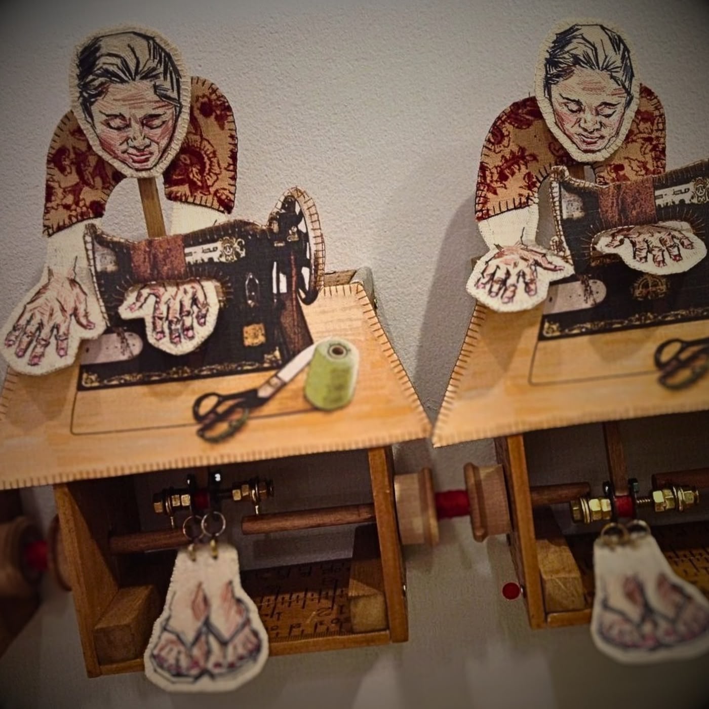 a pair of wooden dolls sewing on the sewing machine