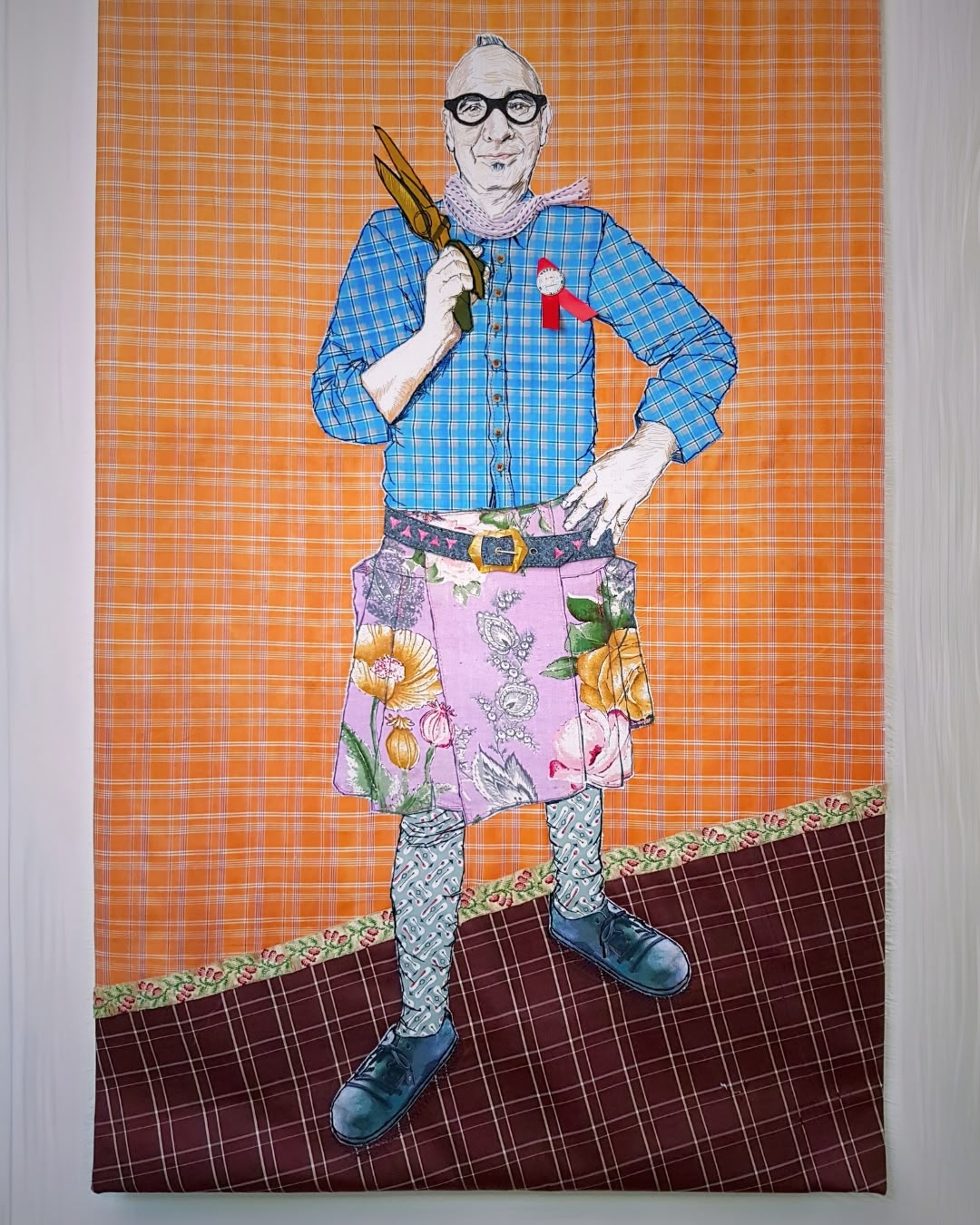 a stitched artwork of a man in a pink kilt holding scissors